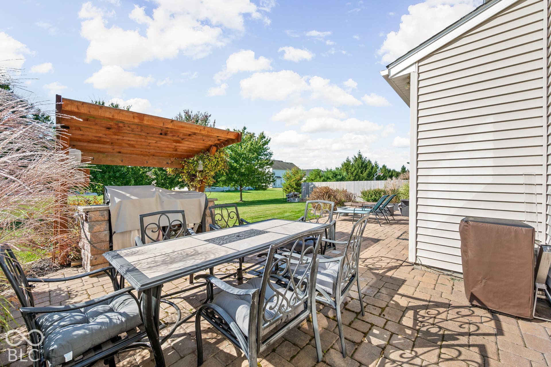Brick paver patio featuring a wood pergola and stone-clad built-in