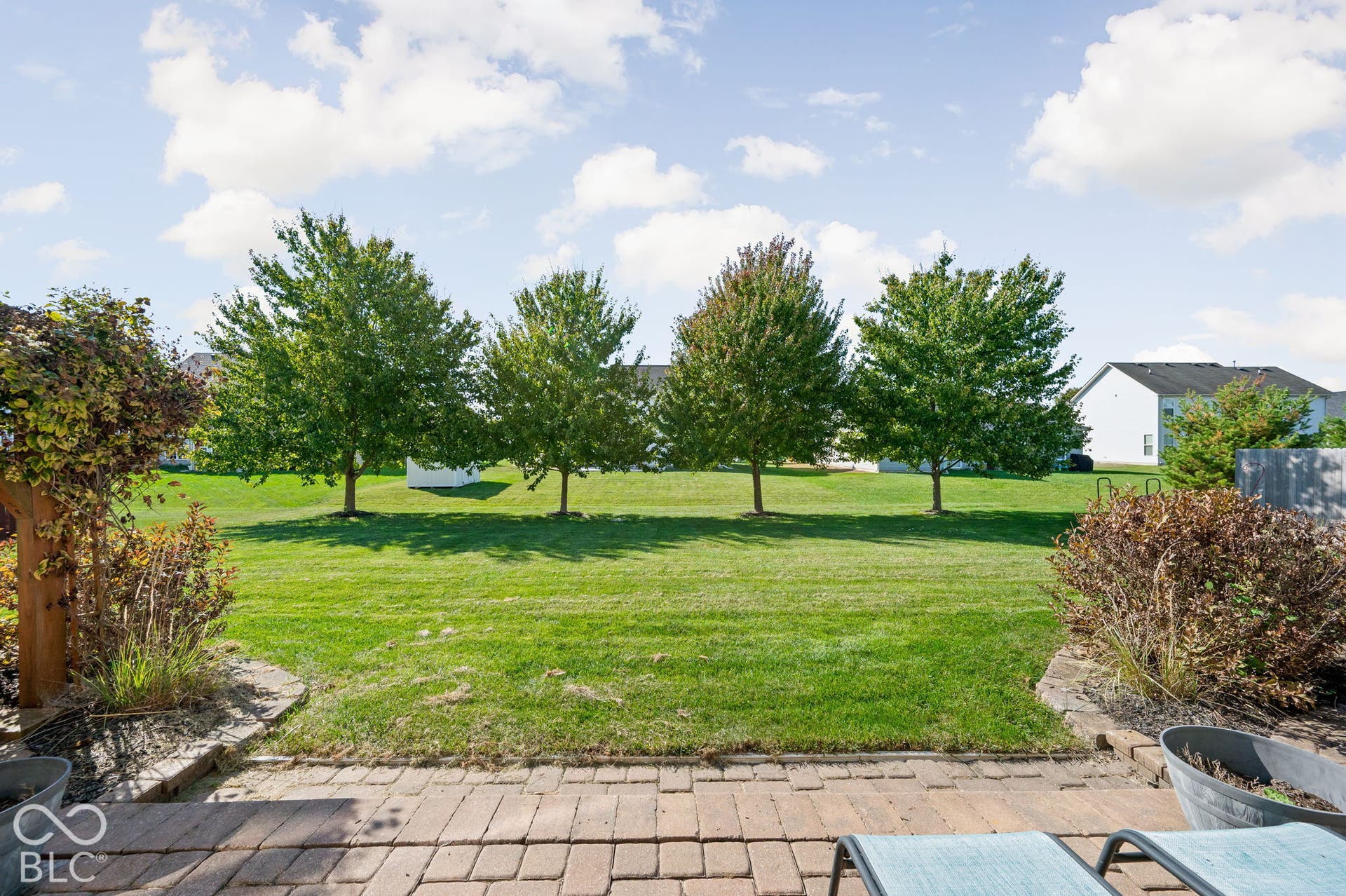 Expansive green lawn, mature trees, brick paver patio, integrated landscaping