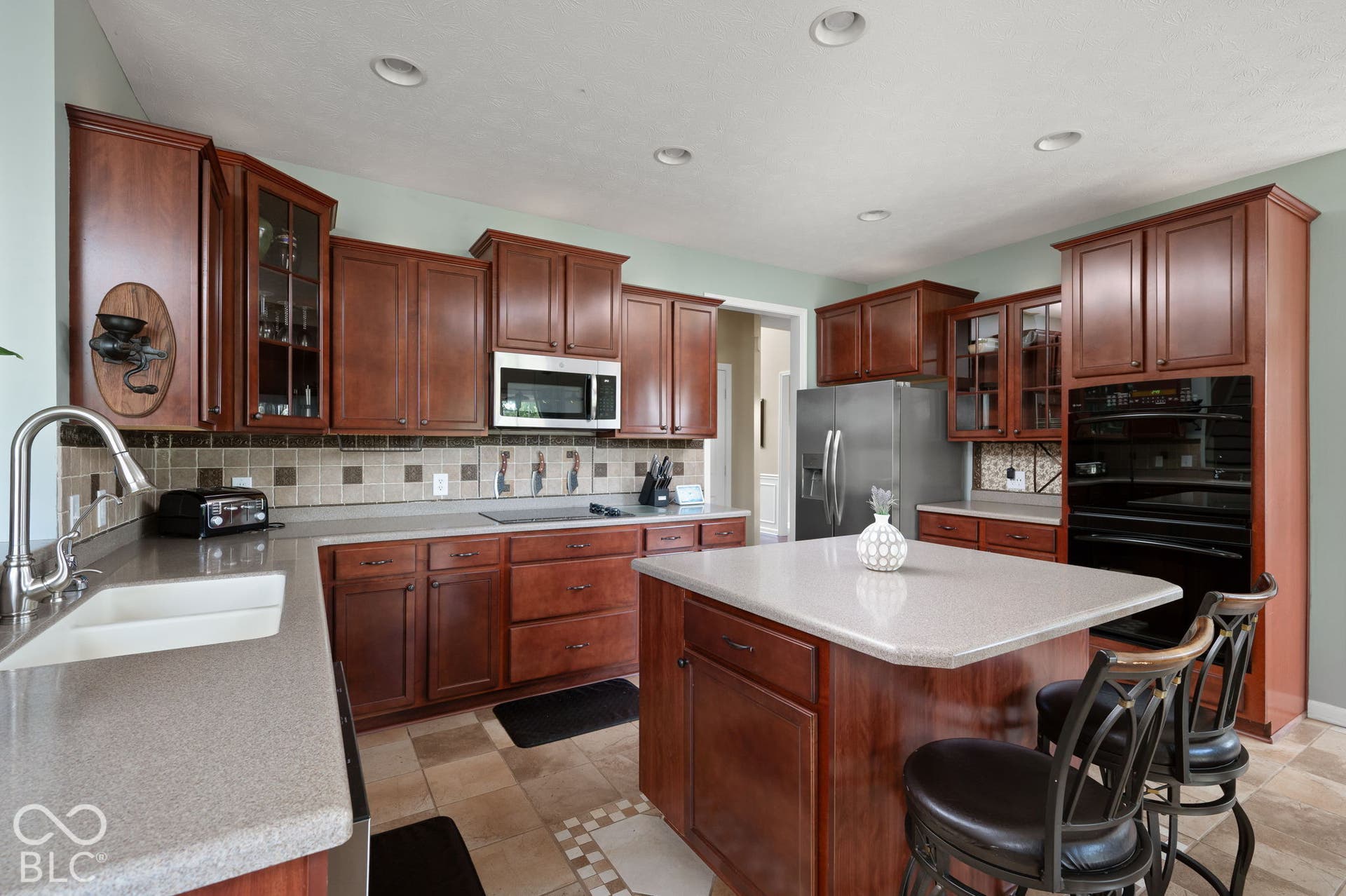 Kitchen featuring extensive wood cabinetry, light-toned countertops, a central island, recessed lighting, and stainless steel appliances