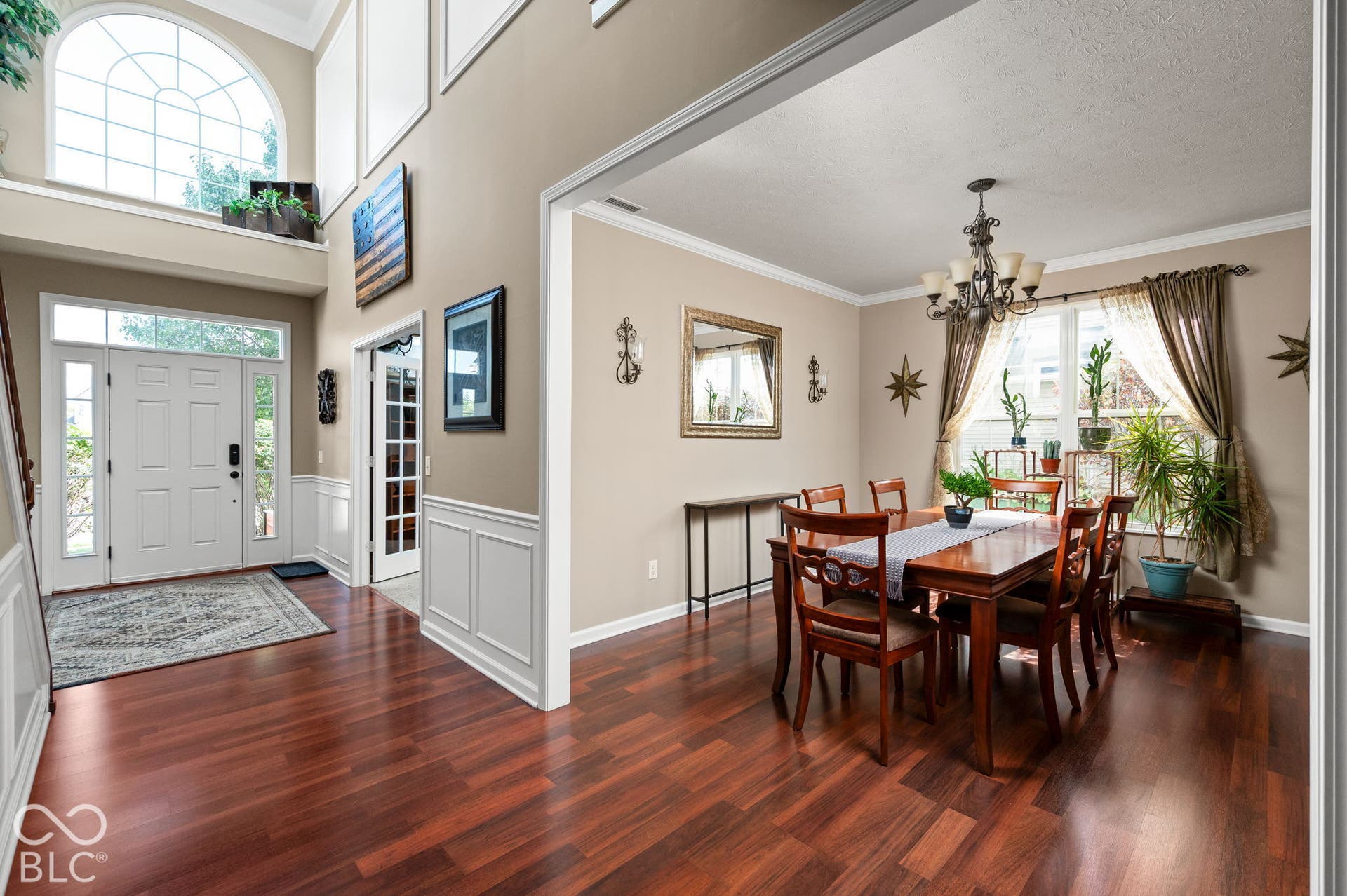 Two-story foyer with an arched transom window and wood-finish flooring