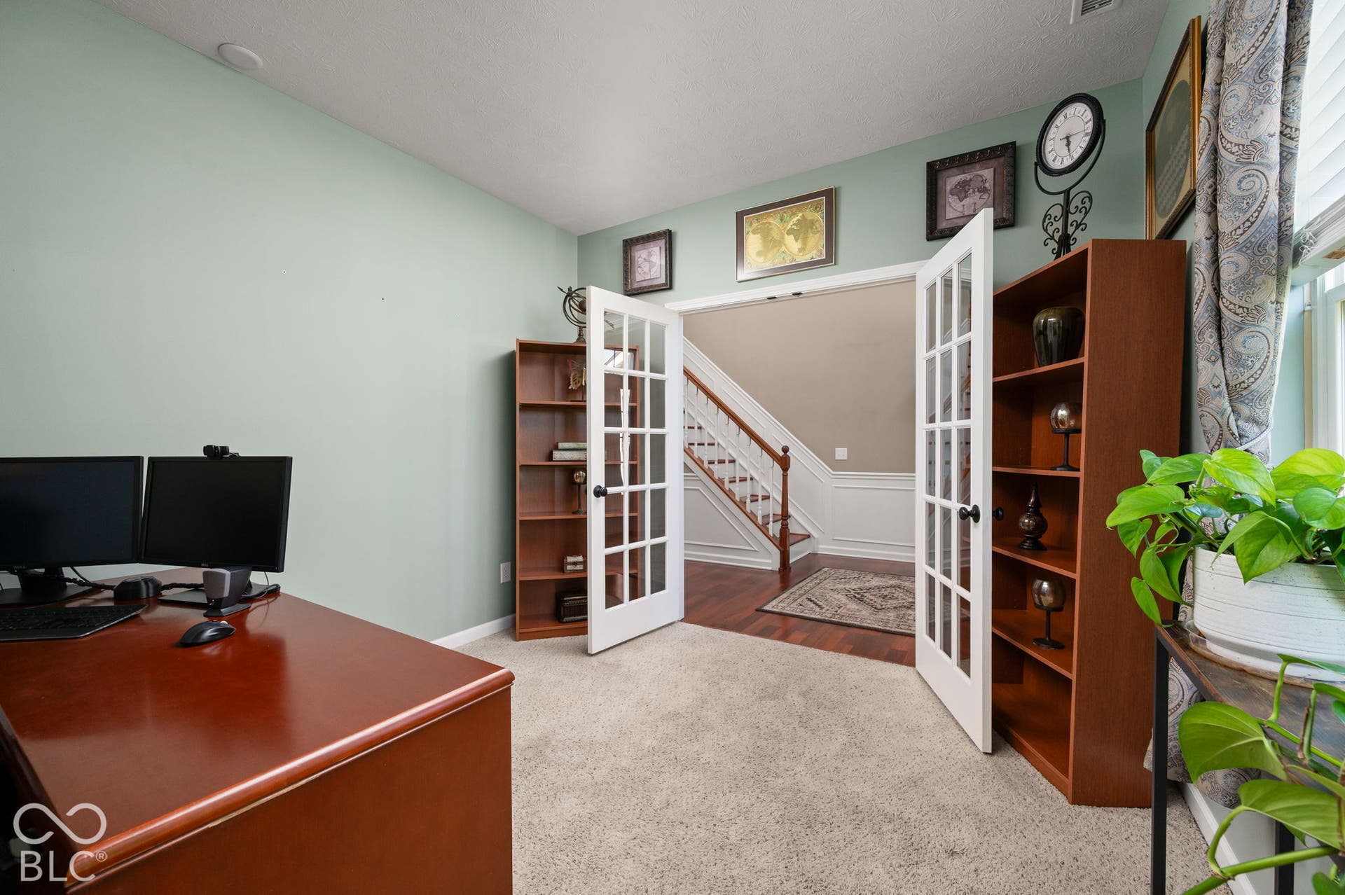Double French doors opening to an entryway with wood flooring and a staircase