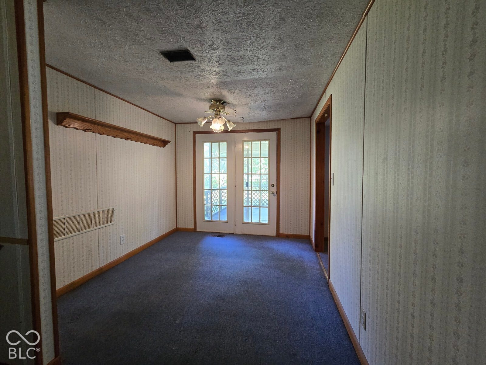 Recessed ceiling, ceiling fan with light fixture, double French doors, patterned wallpaper, and wood trim accents