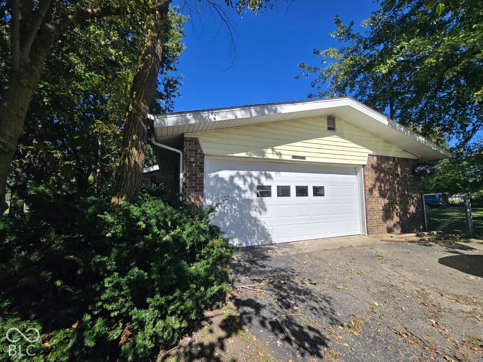 Brick exterior with light-colored siding, attached garage, white garage door with window inserts, and a paved driveway