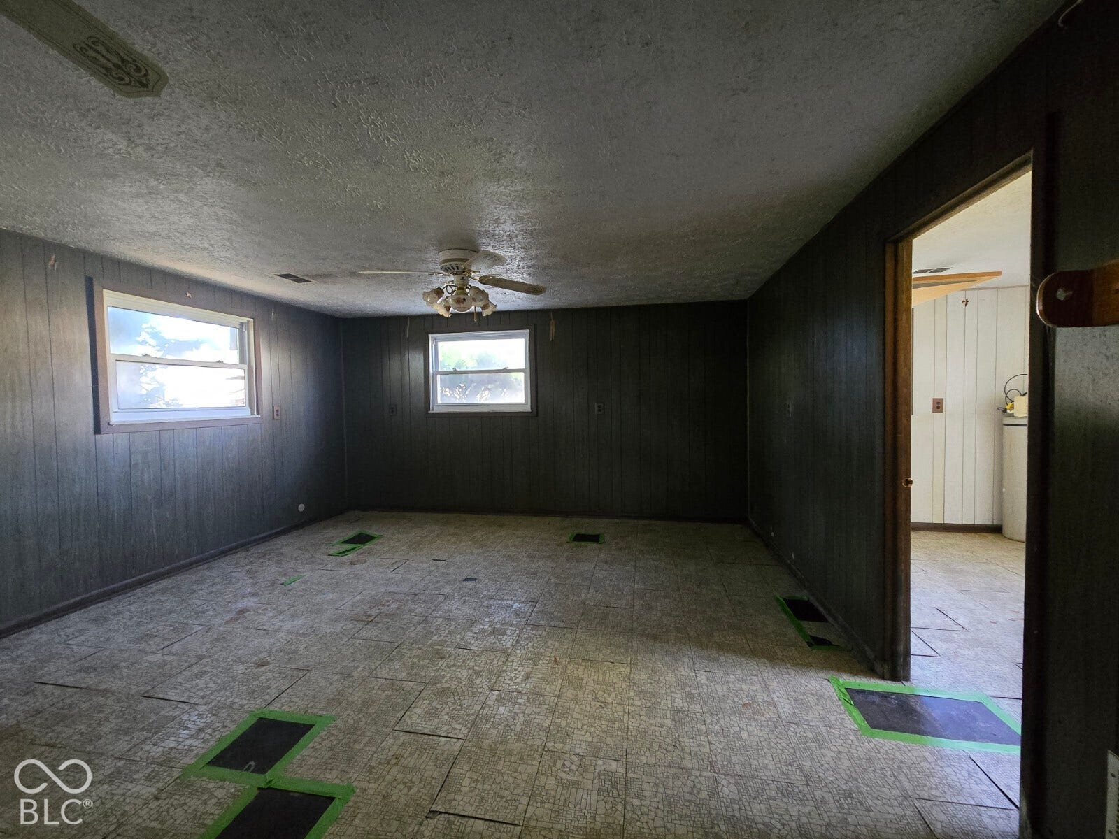 Room featuring two windows, wood-paneled walls, a ceiling fan, and an overhead light fixture
