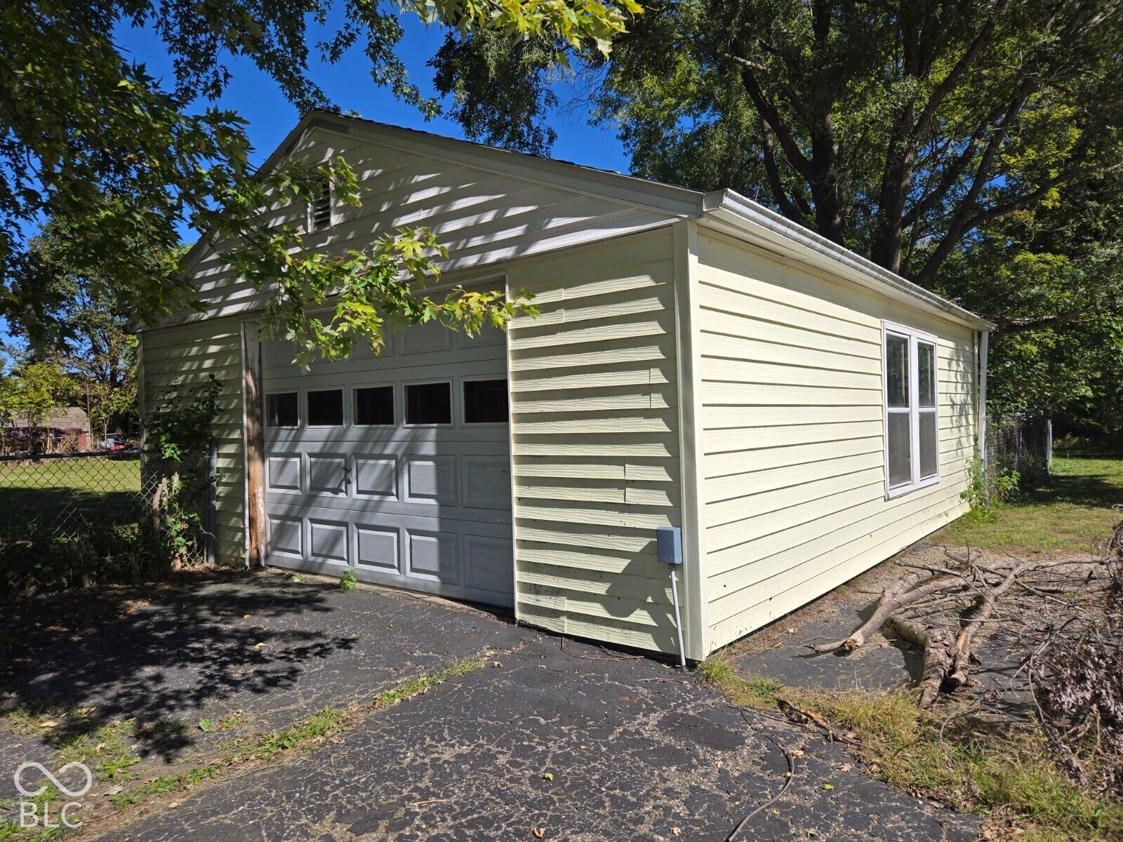 Detached garage with vinyl siding and a single garage door featuring upper window panels