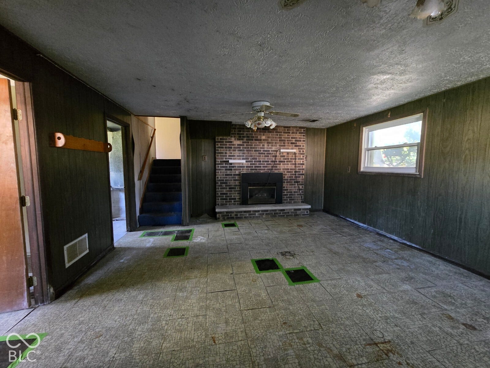 Brick fireplace with a raised hearth, a single-pane window, and a ceiling fan with integrated lighting