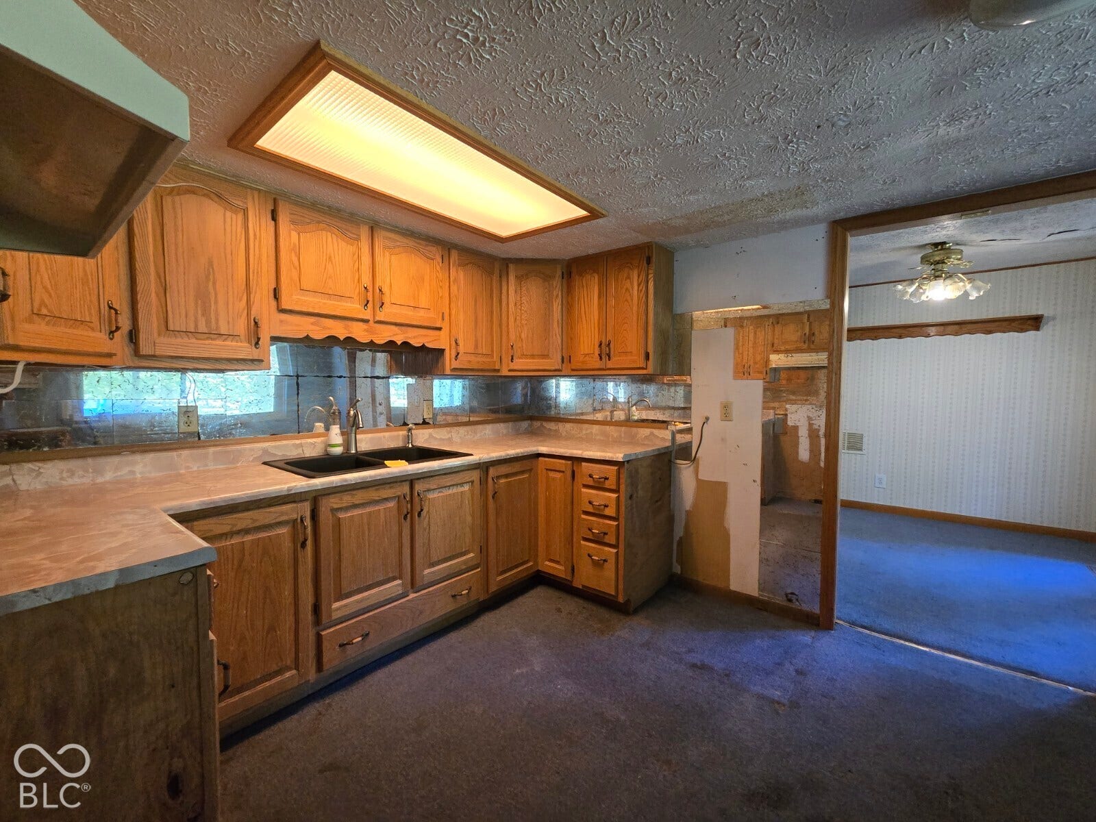 Kitchen featuring wood cabinetry, laminate countertops, an undermount sink with a gooseneck faucet, and a recessed ceiling light
