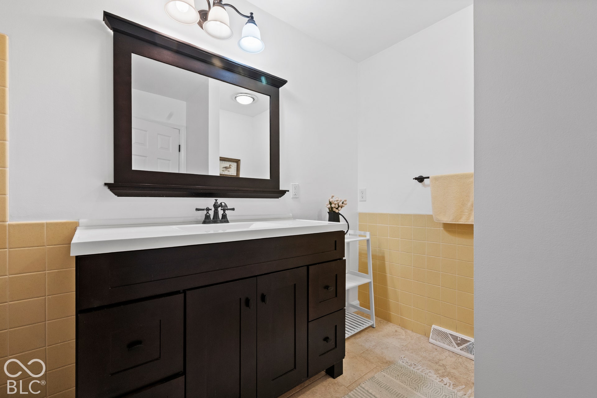 Dark wood-finish vanity with a white countertop and dark-toned faucet