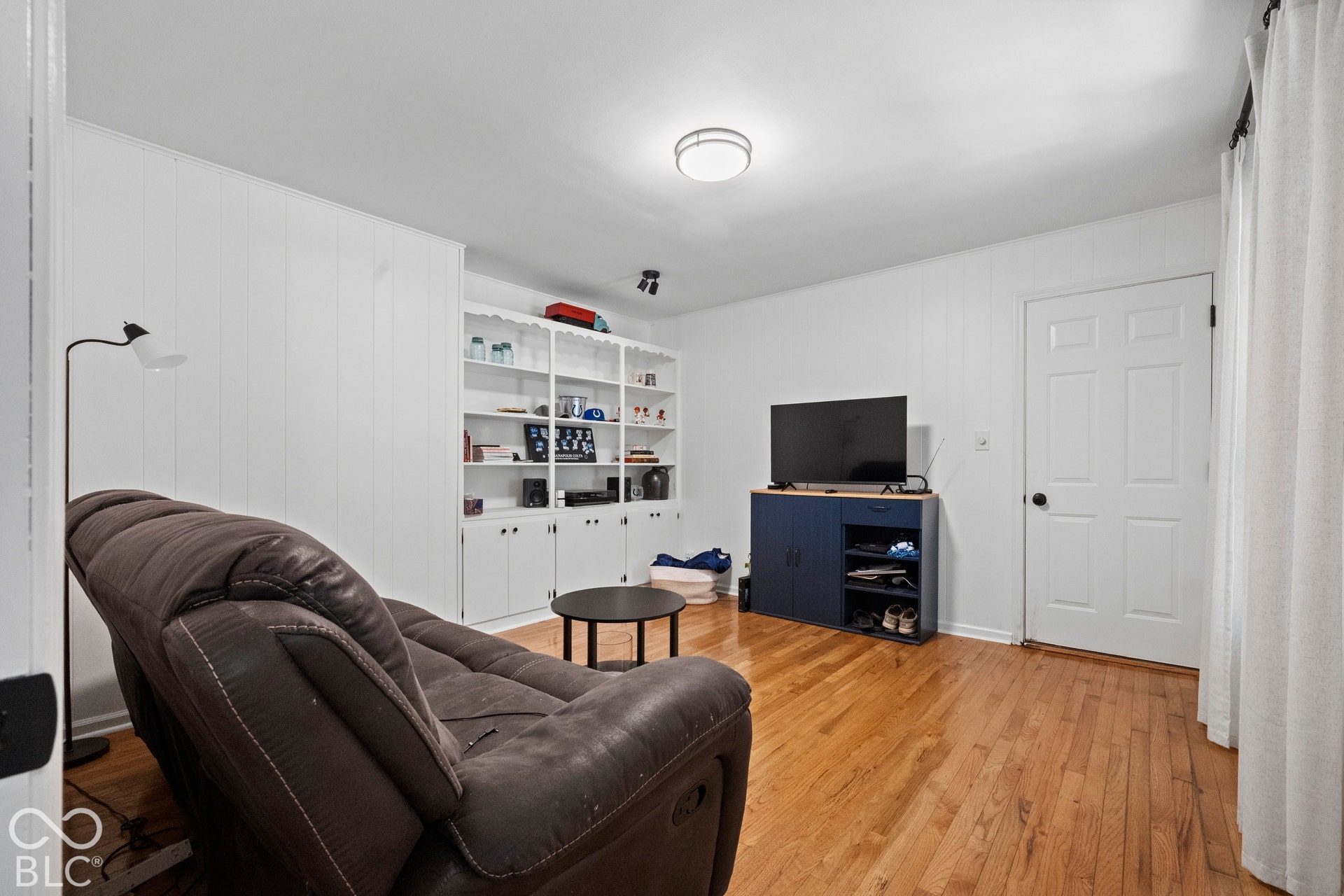 Hardwood flooring, recessed ceiling lighting, built-in shelving, and a paneled interior door