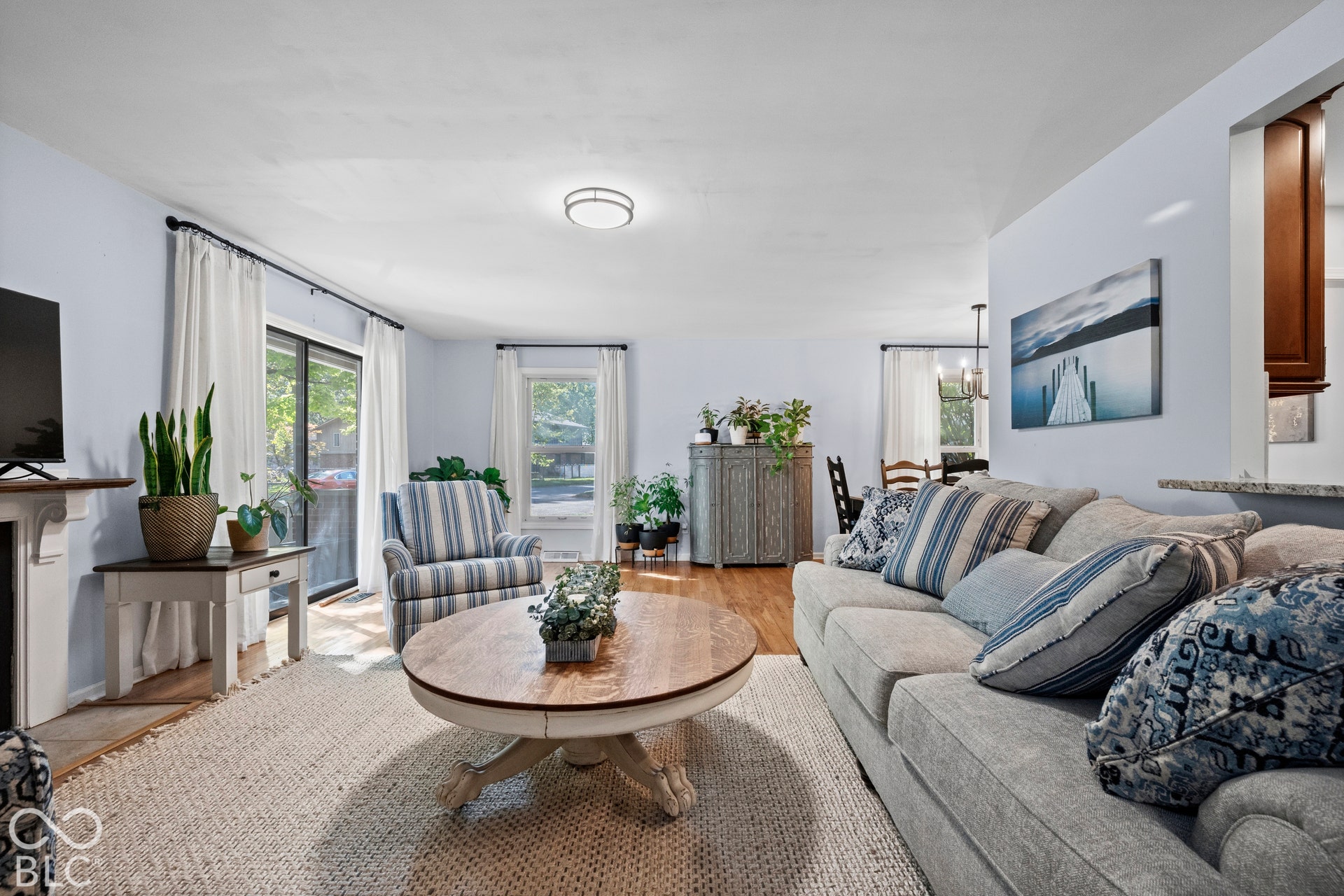 Sliding glass door, wood-finish flooring, recessed lighting, white window treatments, and an open-concept layout