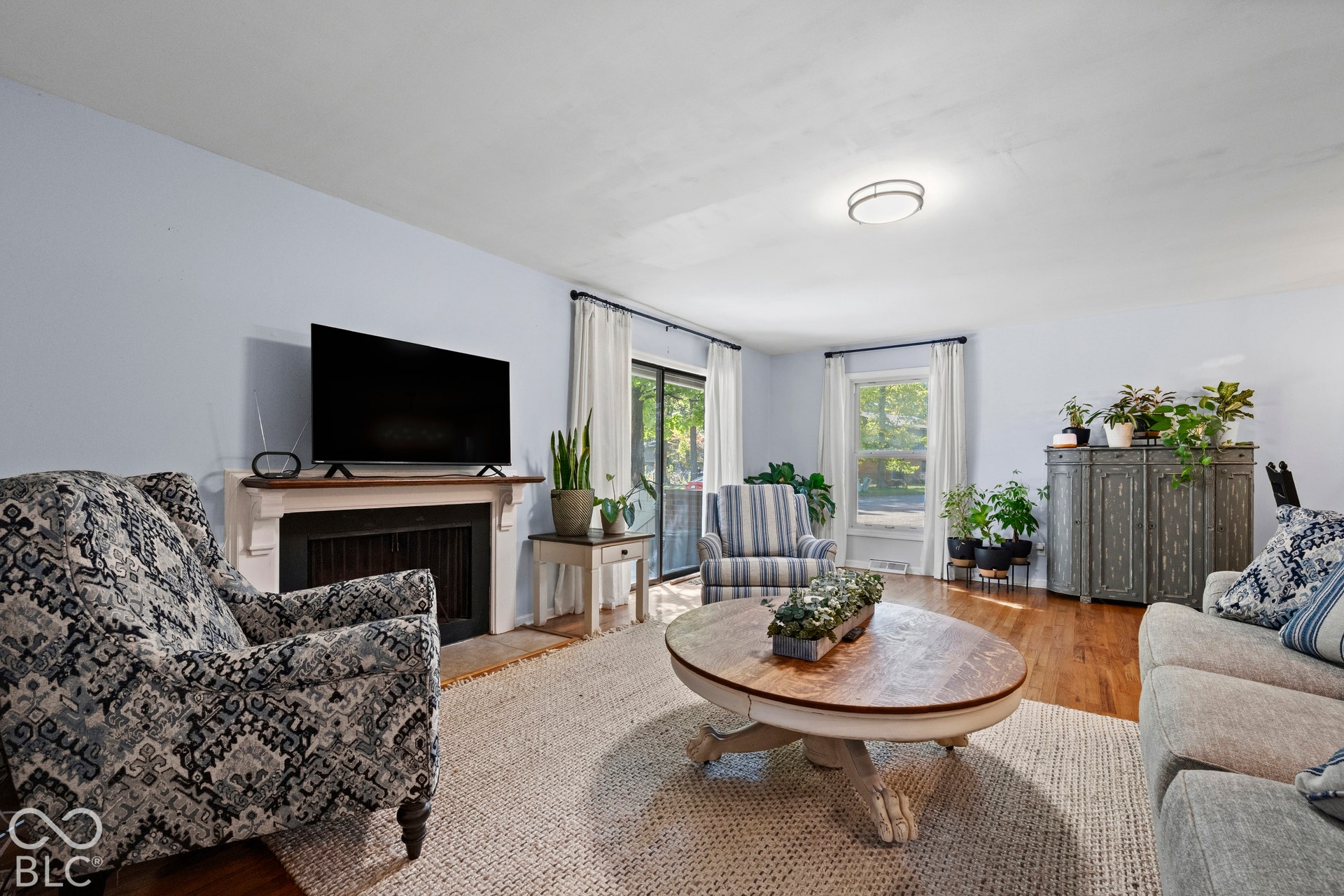 Living area featuring wood-finish flooring, a white mantel, and a sliding glass door