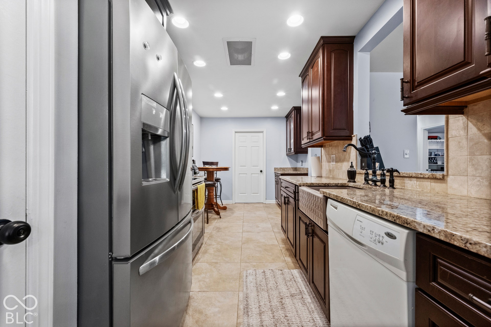 Kitchen featuring stainless steel appliances, dark wood cabinetry, and a farmhouse-style sink