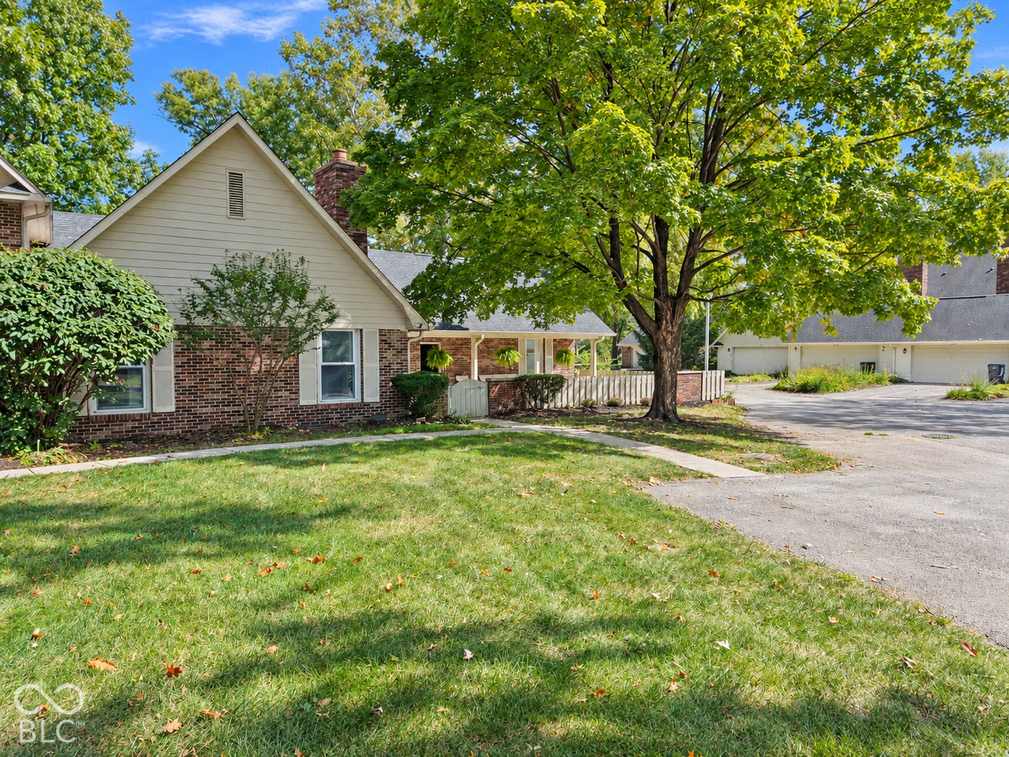 Brick exterior with siding gable, mature trees, and an asphalt driveway