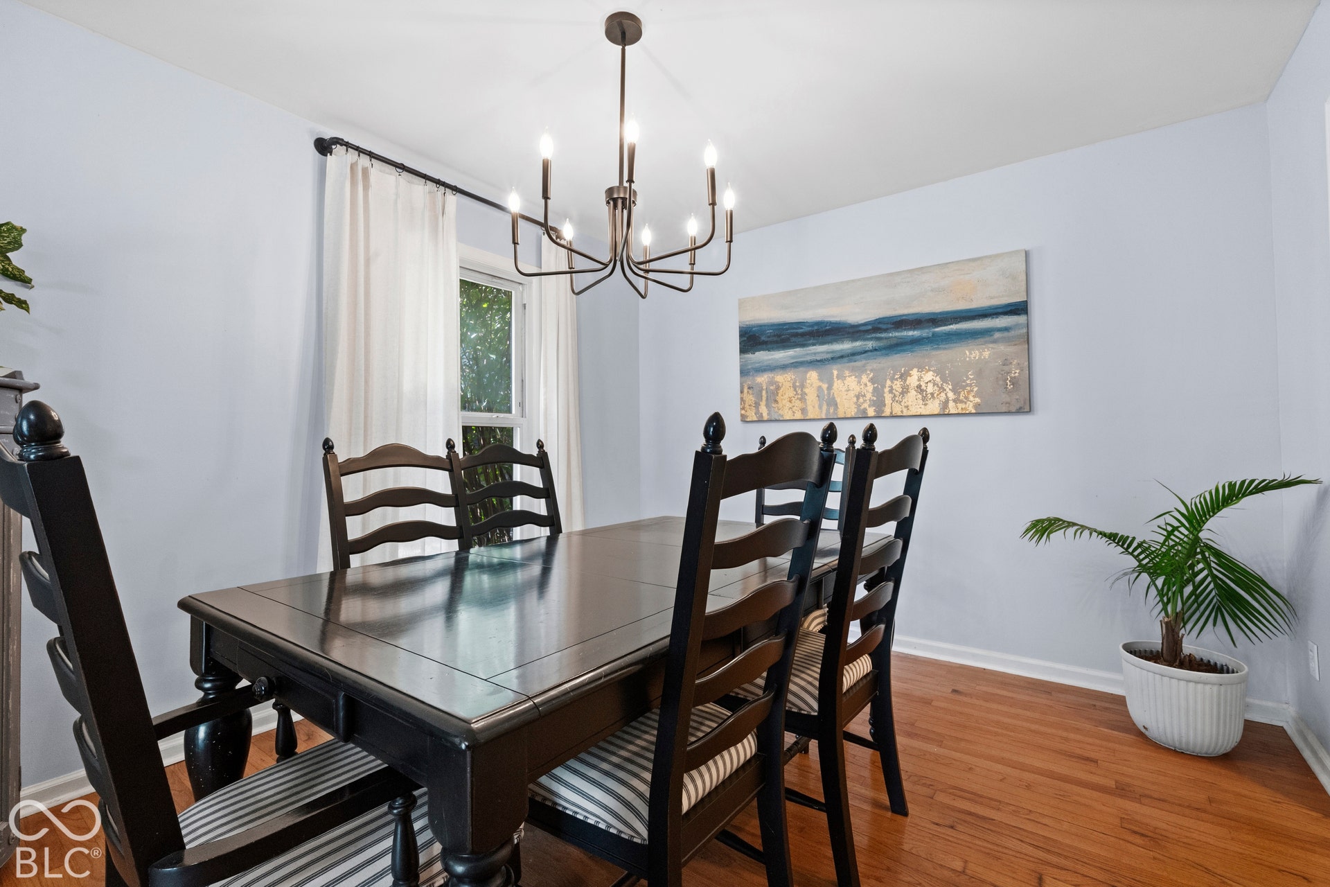 Formal dining room showcasing a dark wood table with seating for six, hardwood flooring, and a modern chandelier with multiple arms