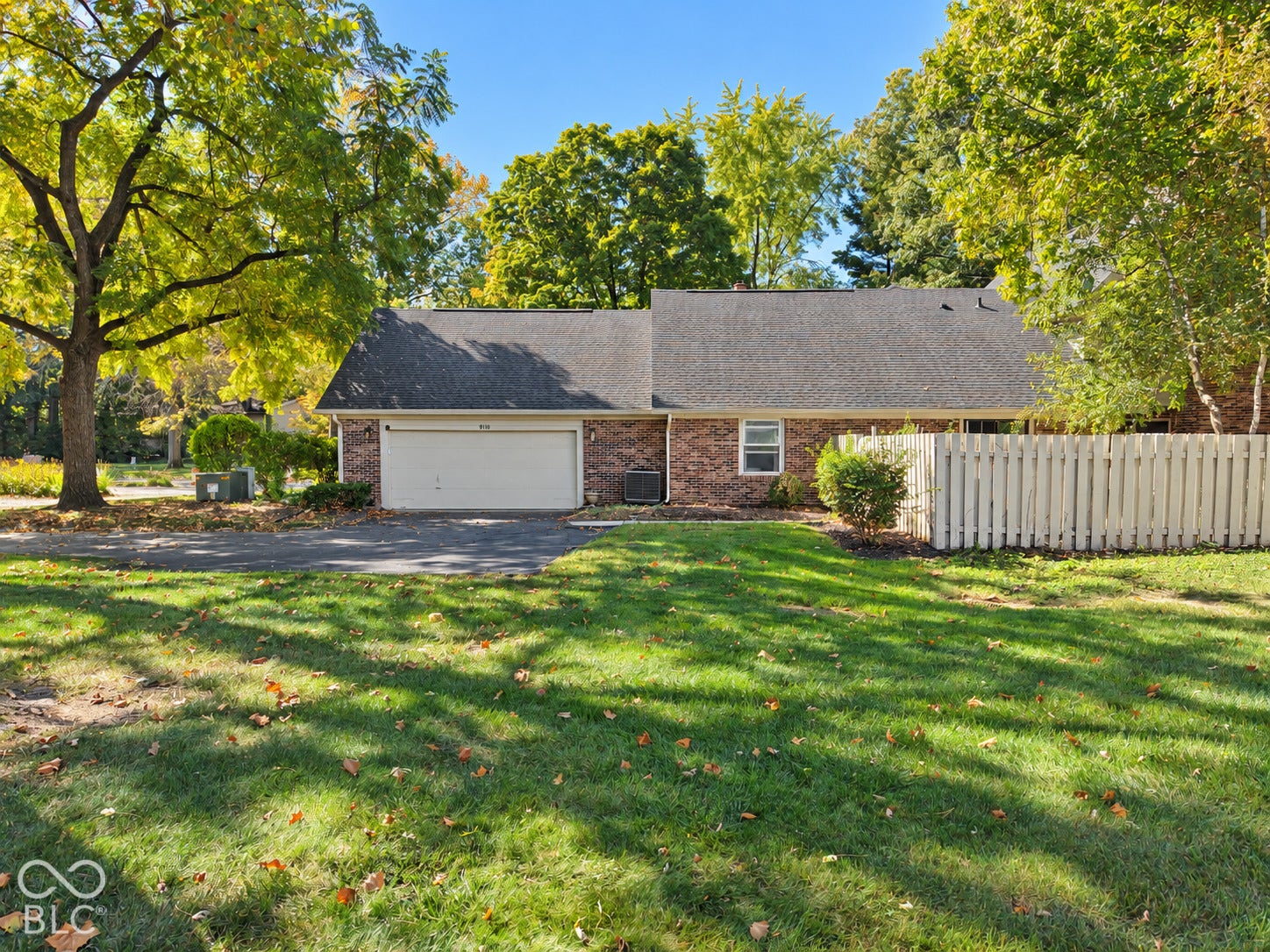 Brick exterior with an attached garage, asphalt driveway, and a fenced yard