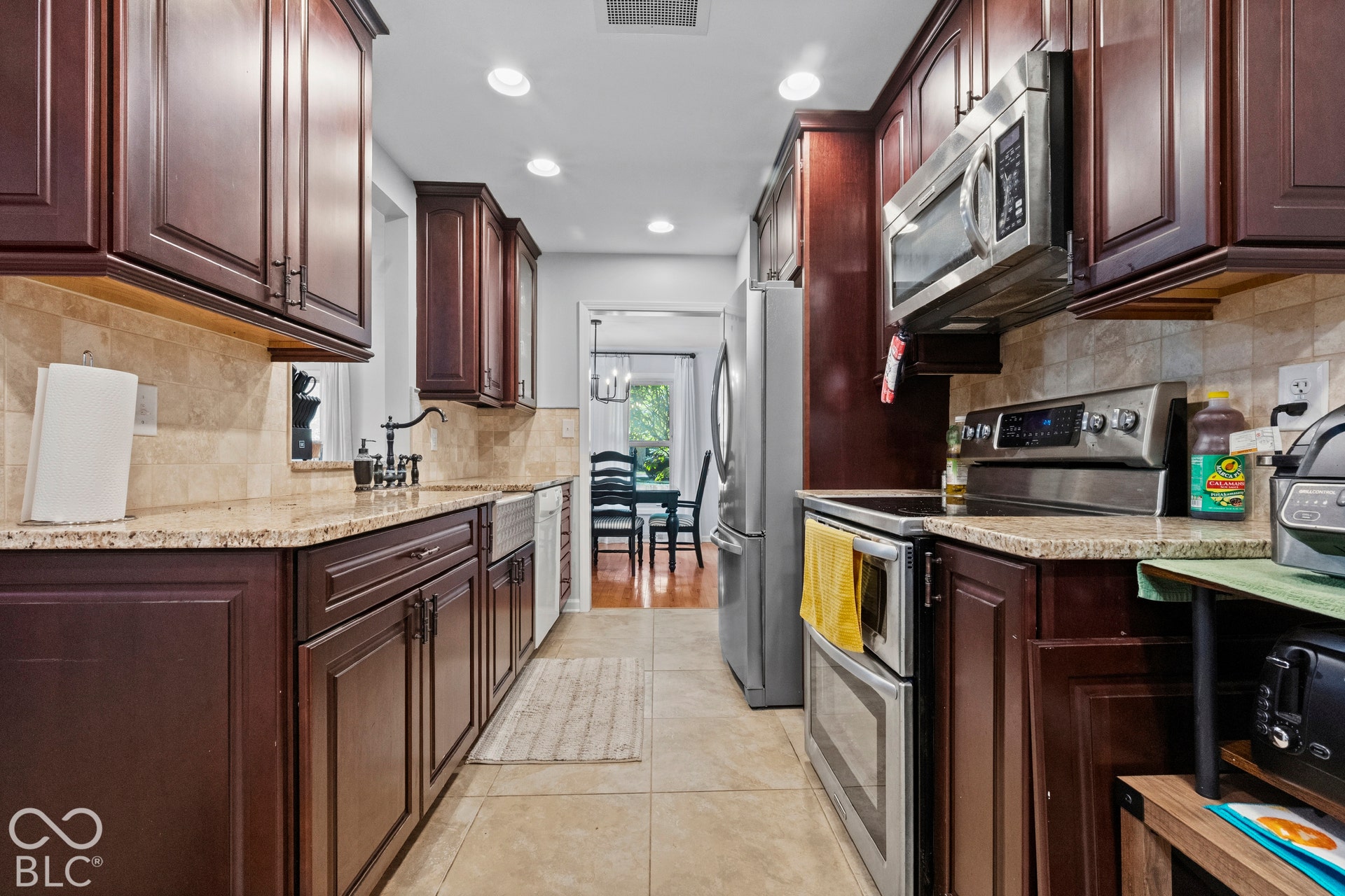 Galley kitchen featuring dark wood cabinetry, light-toned countertops, and a tiled backsplash