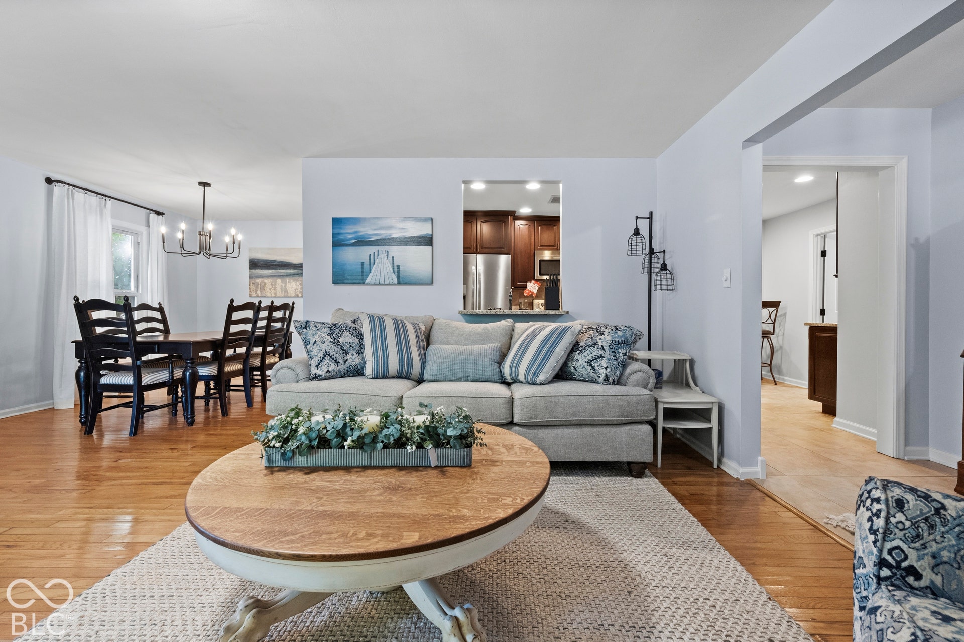 Wood-finish flooring, recessed lighting, and a kitchen pass-through window with dark wood cabinetry