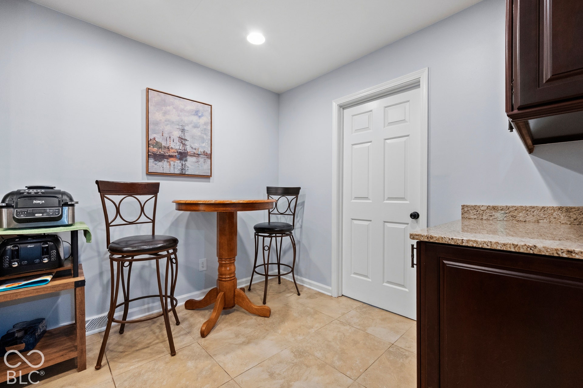 Tile flooring, recessed lighting, white paneled door, dark wood-finish cabinetry, and speckled countertop