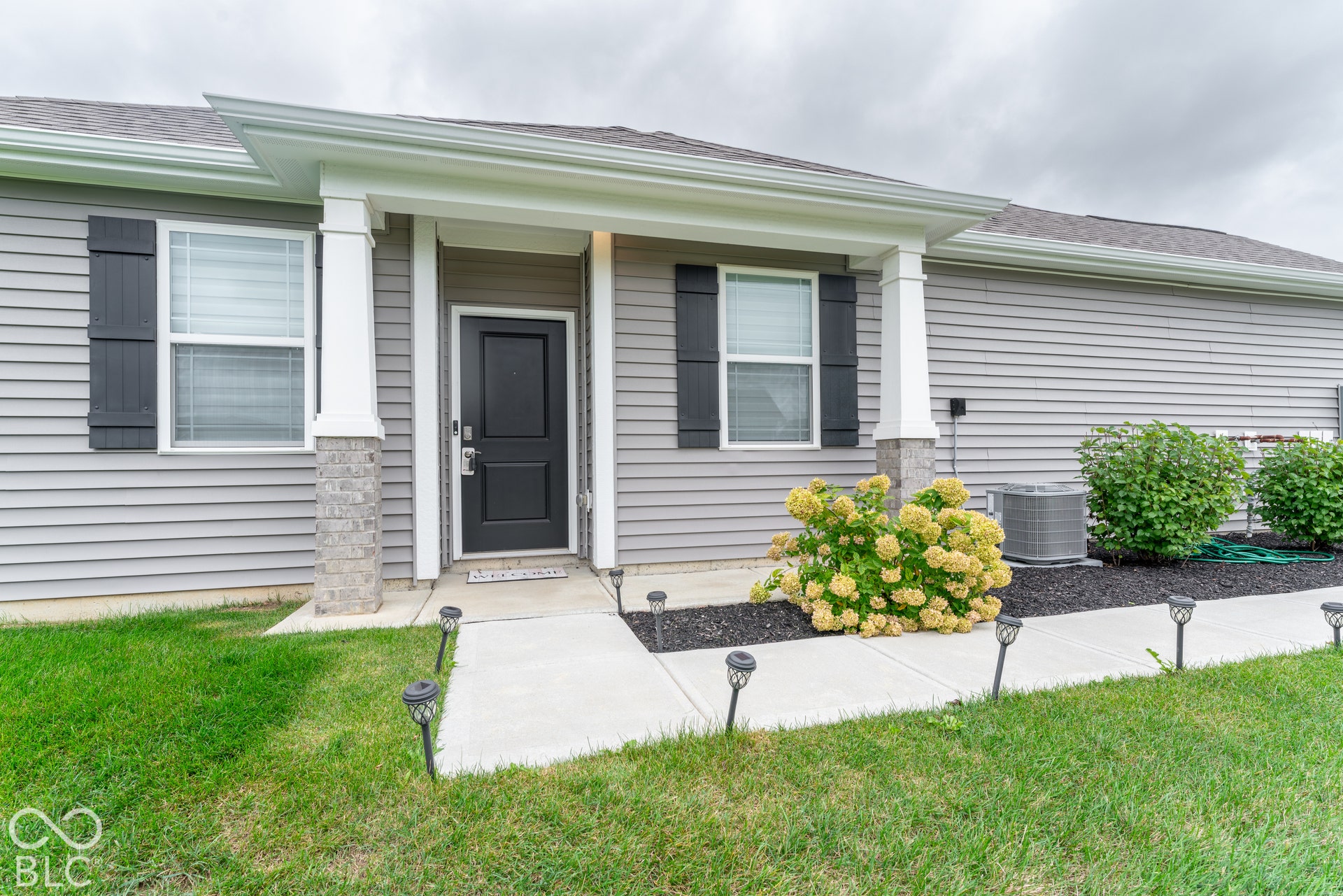6432 Yuma, Whitestown, IN 46075 Grey siding exterior with a covered entry, decorative stone column base, and dark shutters
