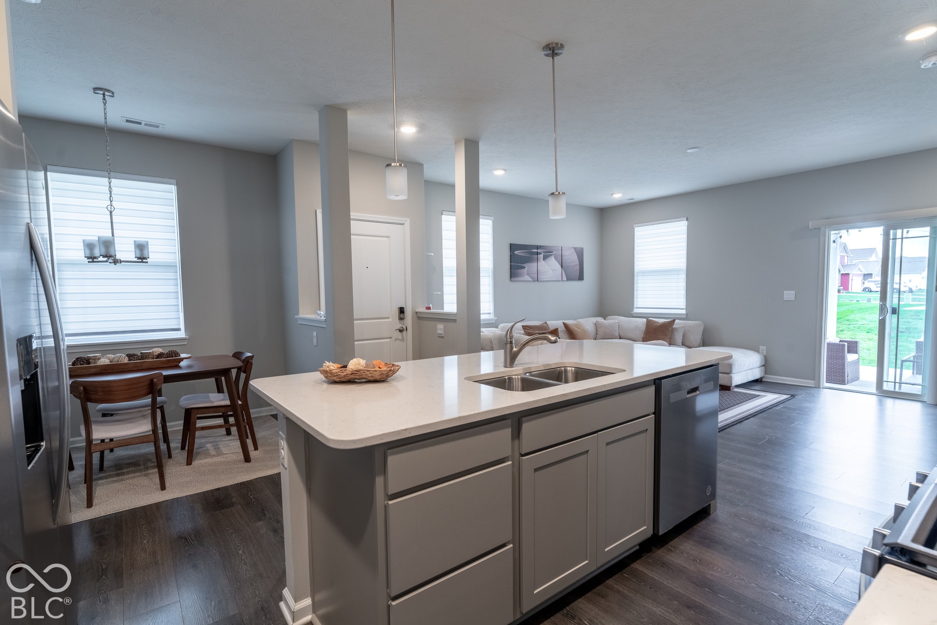 6432 Yuma, Whitestown, IN 46075 Open-concept living space featuring wood-finish flooring, a kitchen island with dual sinks, stainless steel appliances, and sliding glass doors to the exterior