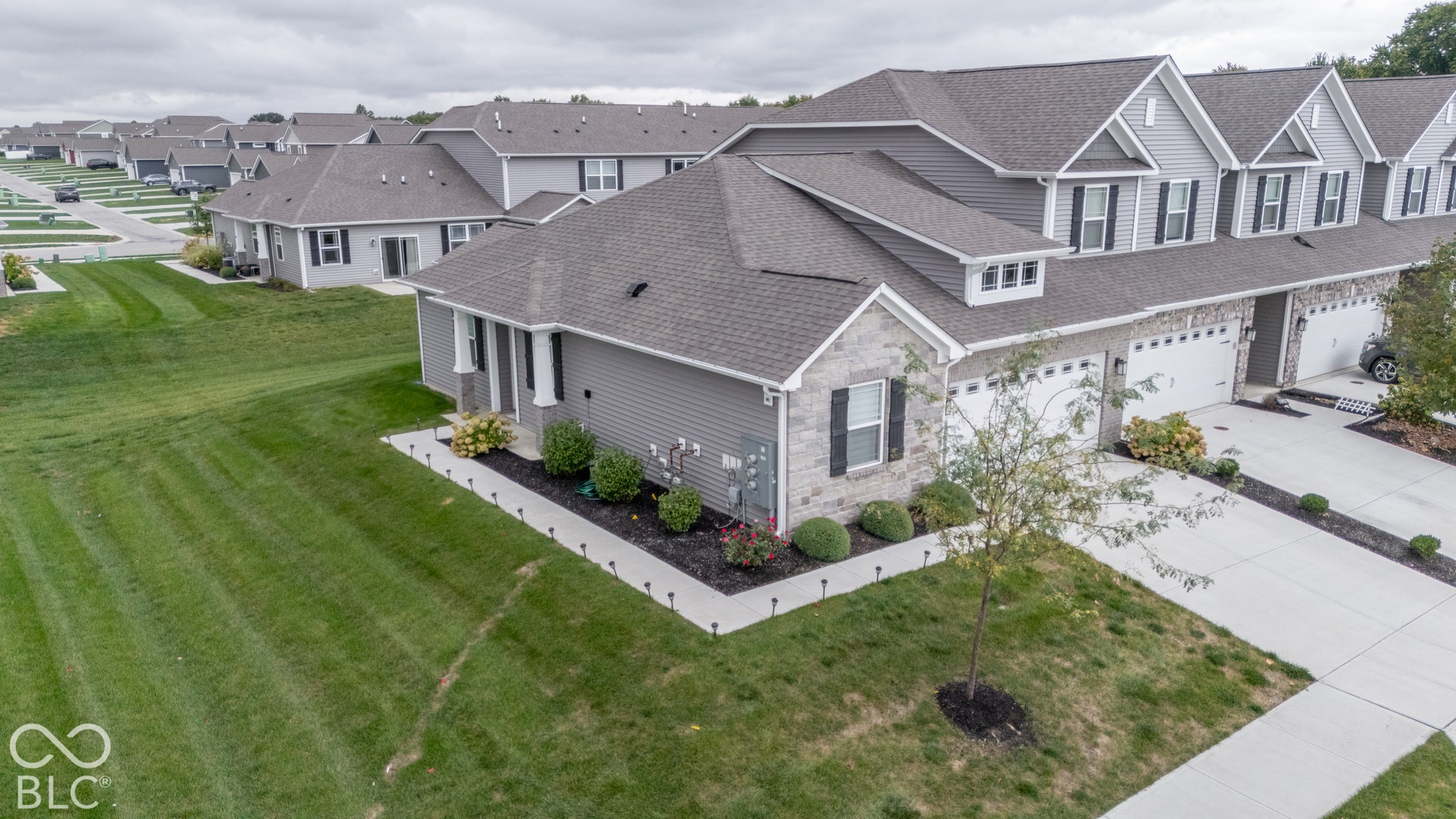 6432 Yuma, Whitestown, IN 46075 Attached garage, gray siding exterior, stone facade accents, dark gray shingle roof, and a concrete driveway