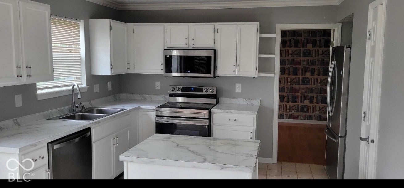 702 Coffee Tree, Indianapolis, IN 46224 White cabinetry, stainless steel appliances, marble-look countertops, kitchen island, and crown molding