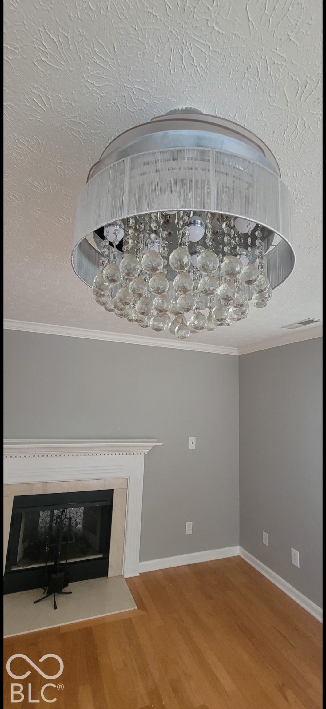 702 Coffee Tree, Indianapolis, IN 46224 Crystal chandelier, hardwood flooring, fireplace with white mantel, light gray wall paint, and white crown molding