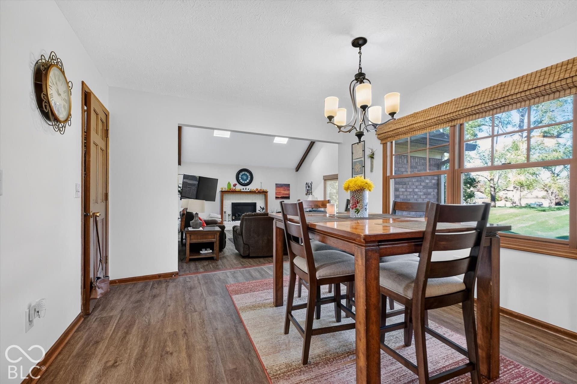 Dining area with wood-finish flooring, high ceilings with pendant lighting, and expansive windows framing natural light