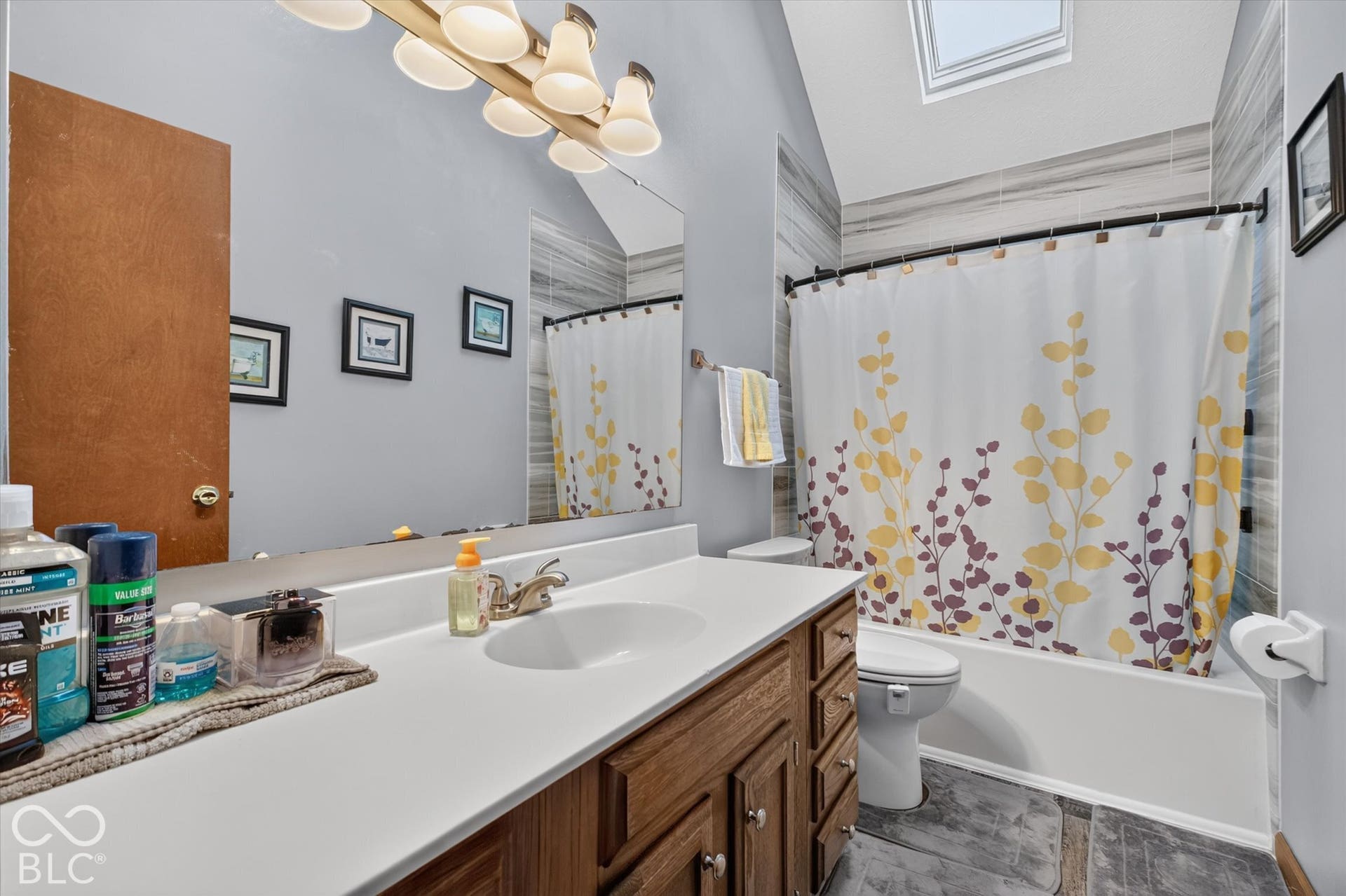 Vanity with integrated sink, wood-finish cabinetry, and a full-width mirror