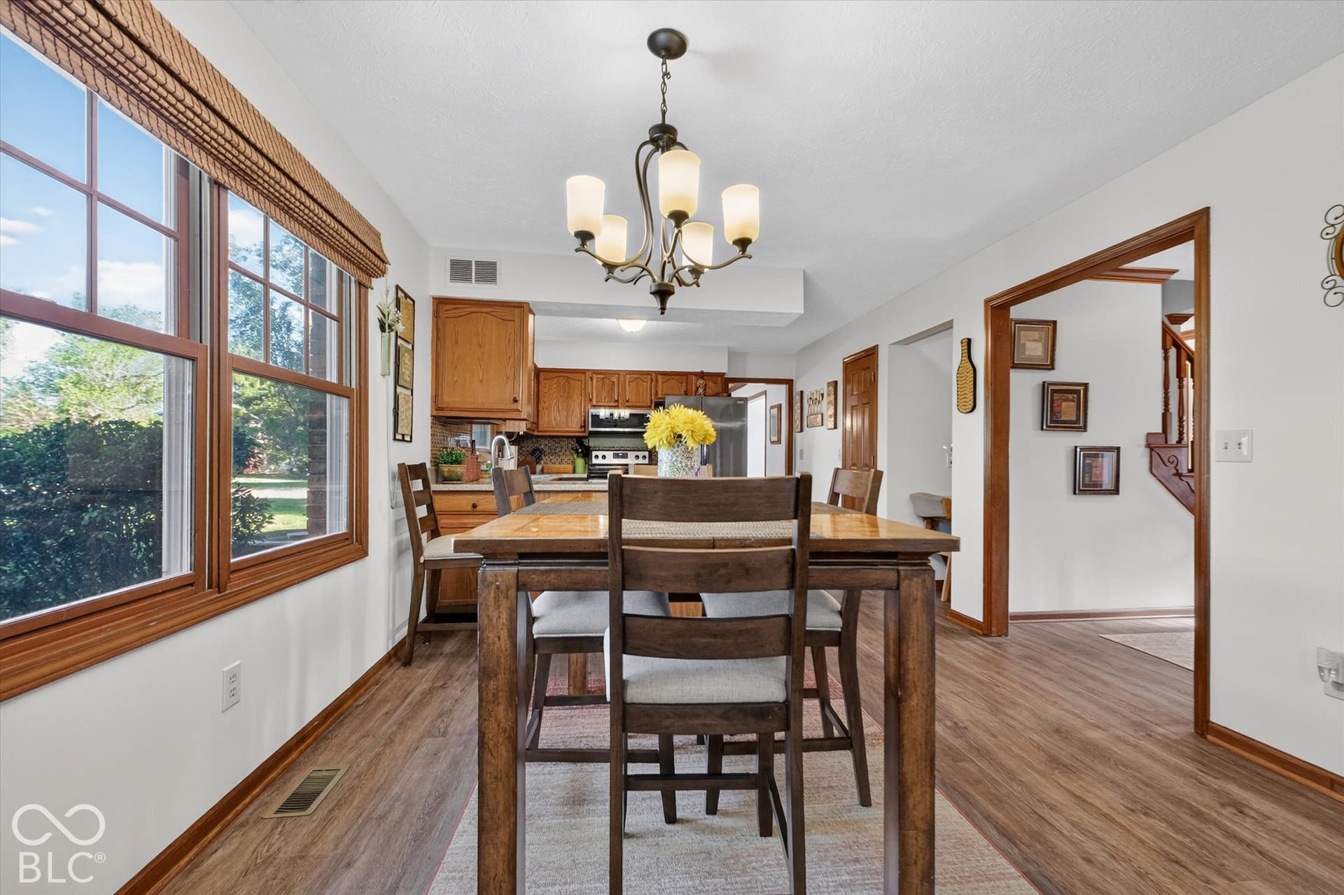 Open-concept living area featuring wood-finish flooring, a chandelier, and a large window with wood trim