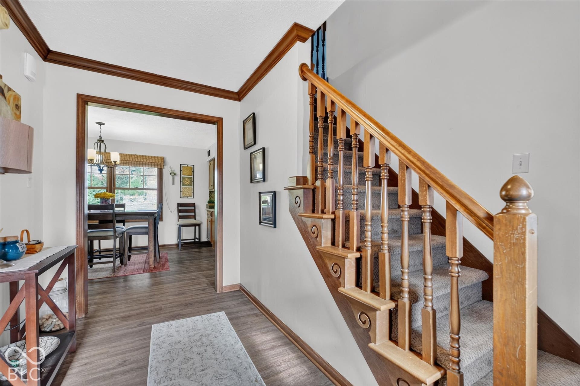 Wood-finish flooring, staircase with natural wood balusters and newel post, and a carpeted runner