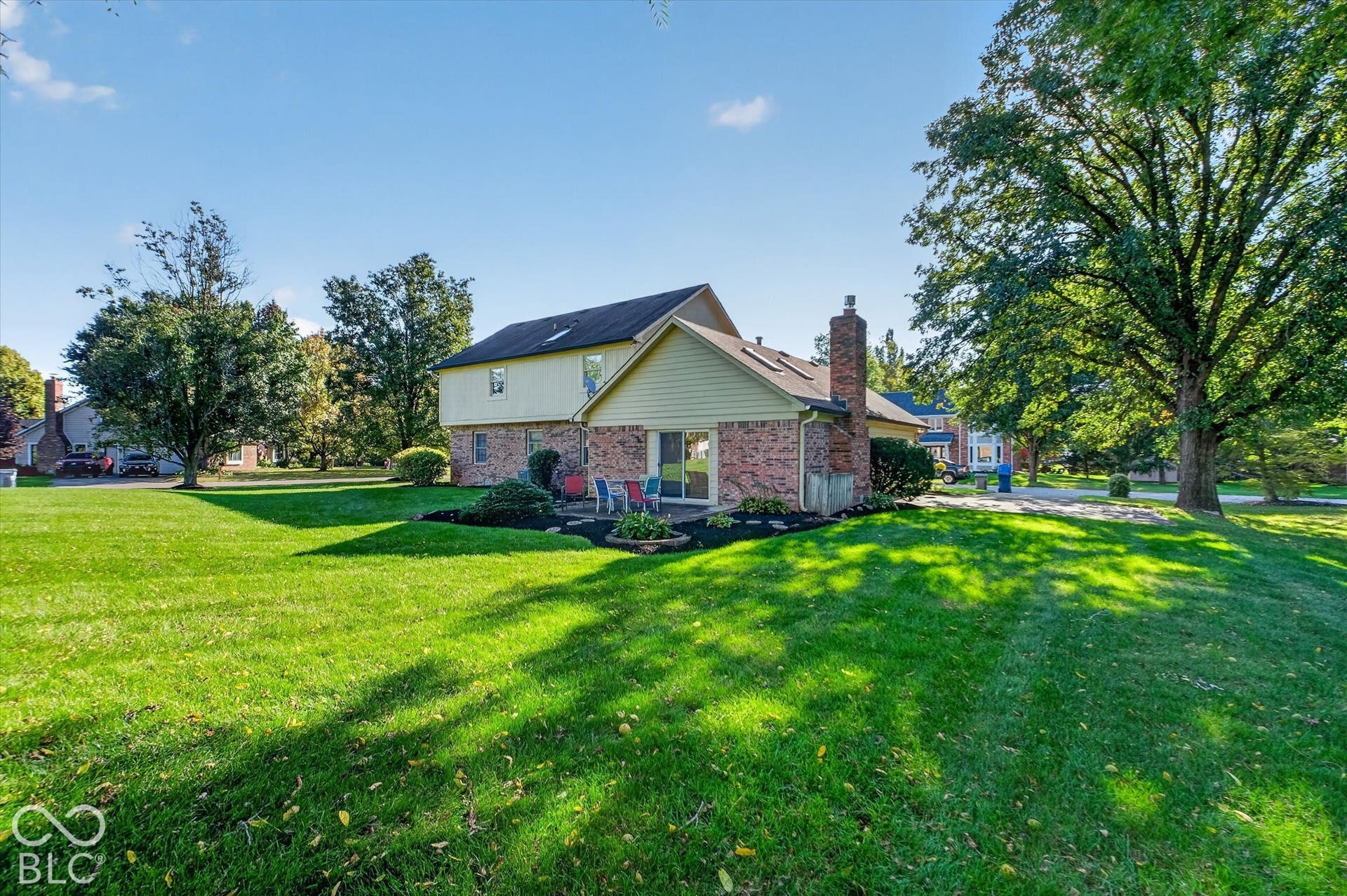 Expansive green lawn with mature trees and a brick and siding exterior