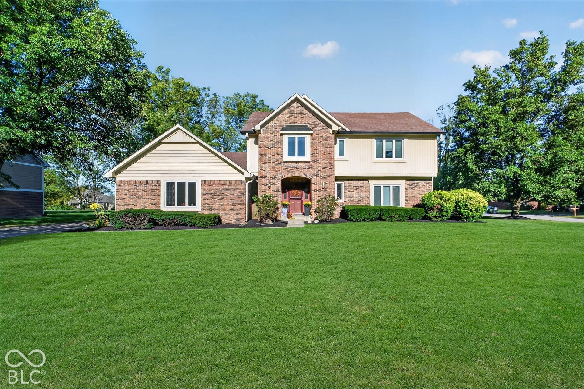Brick and stone Colonial-style residence featuring a two-story design with peaked rooflines, arched entry, and multi-pane windows