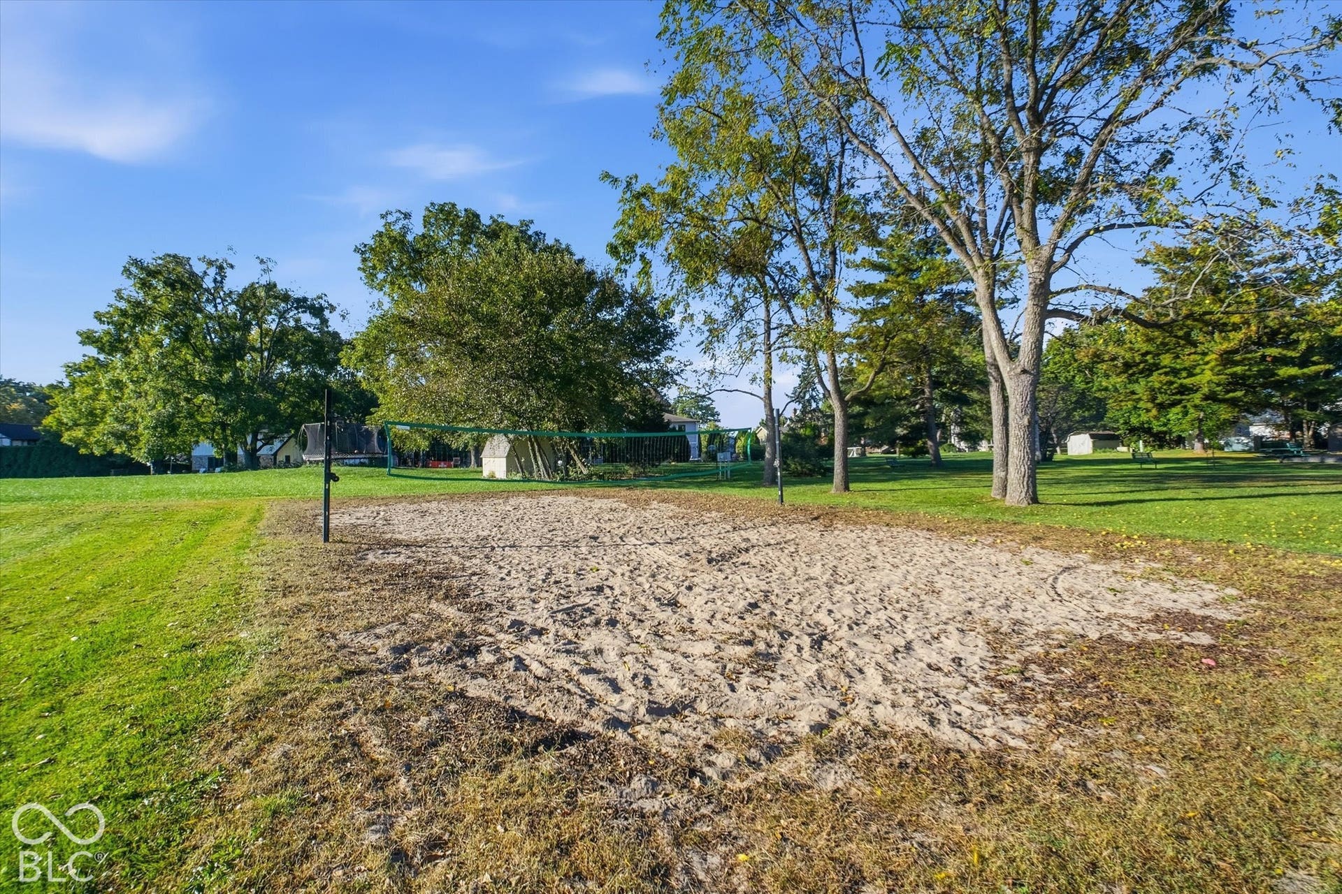 Sand volleyball court with net and surrounding green space