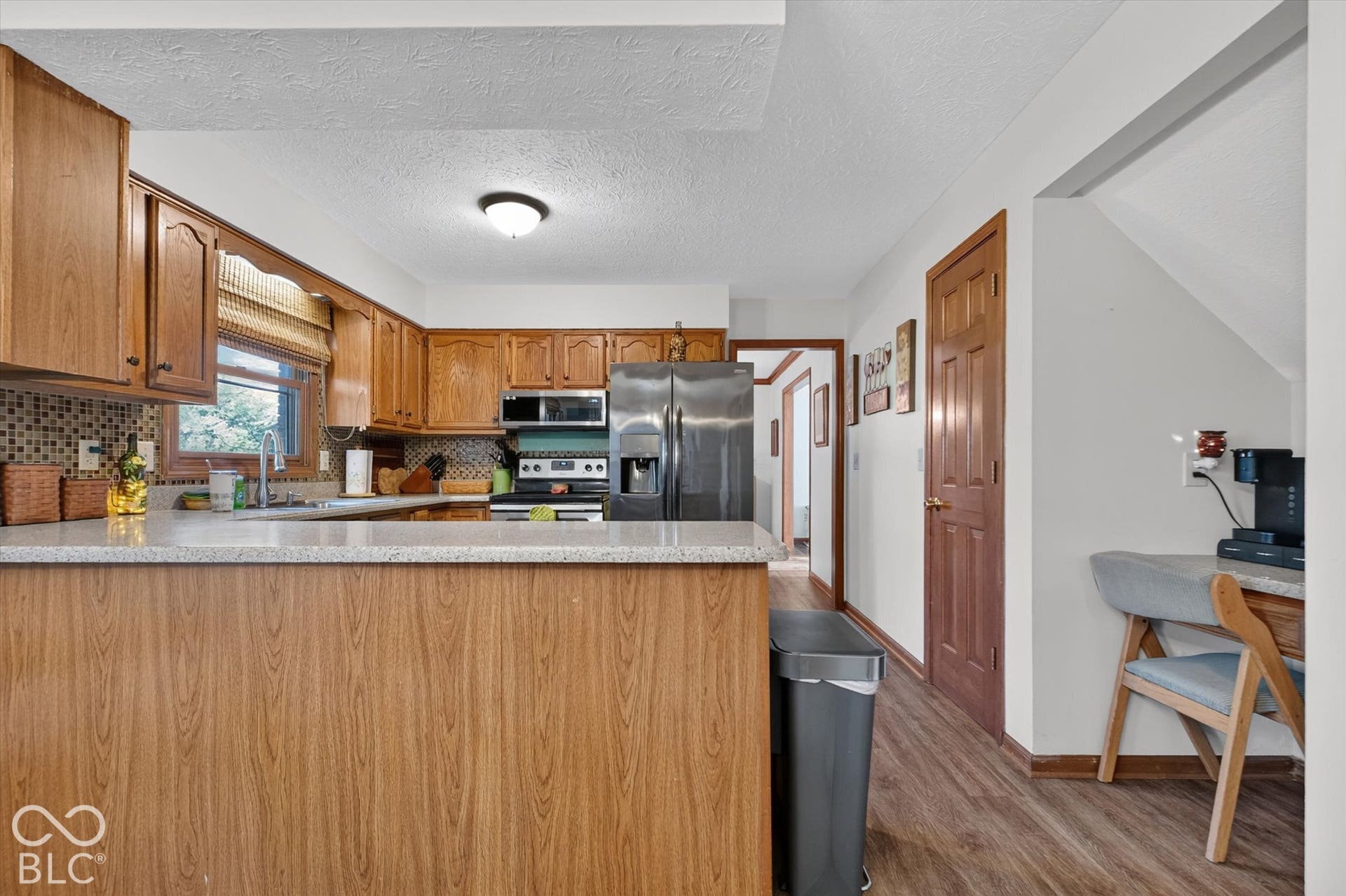 Wood-finish flooring, stone-look countertops, wood cabinetry, and stainless steel appliances