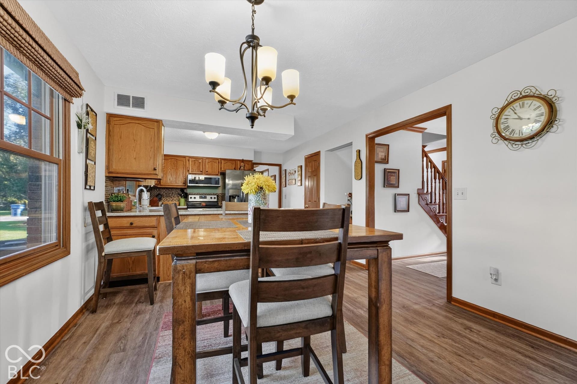 Wood-finish flooring throughout, with a window featuring wood trim, and a kitchen area with wood cabinetry and a tile backsplash