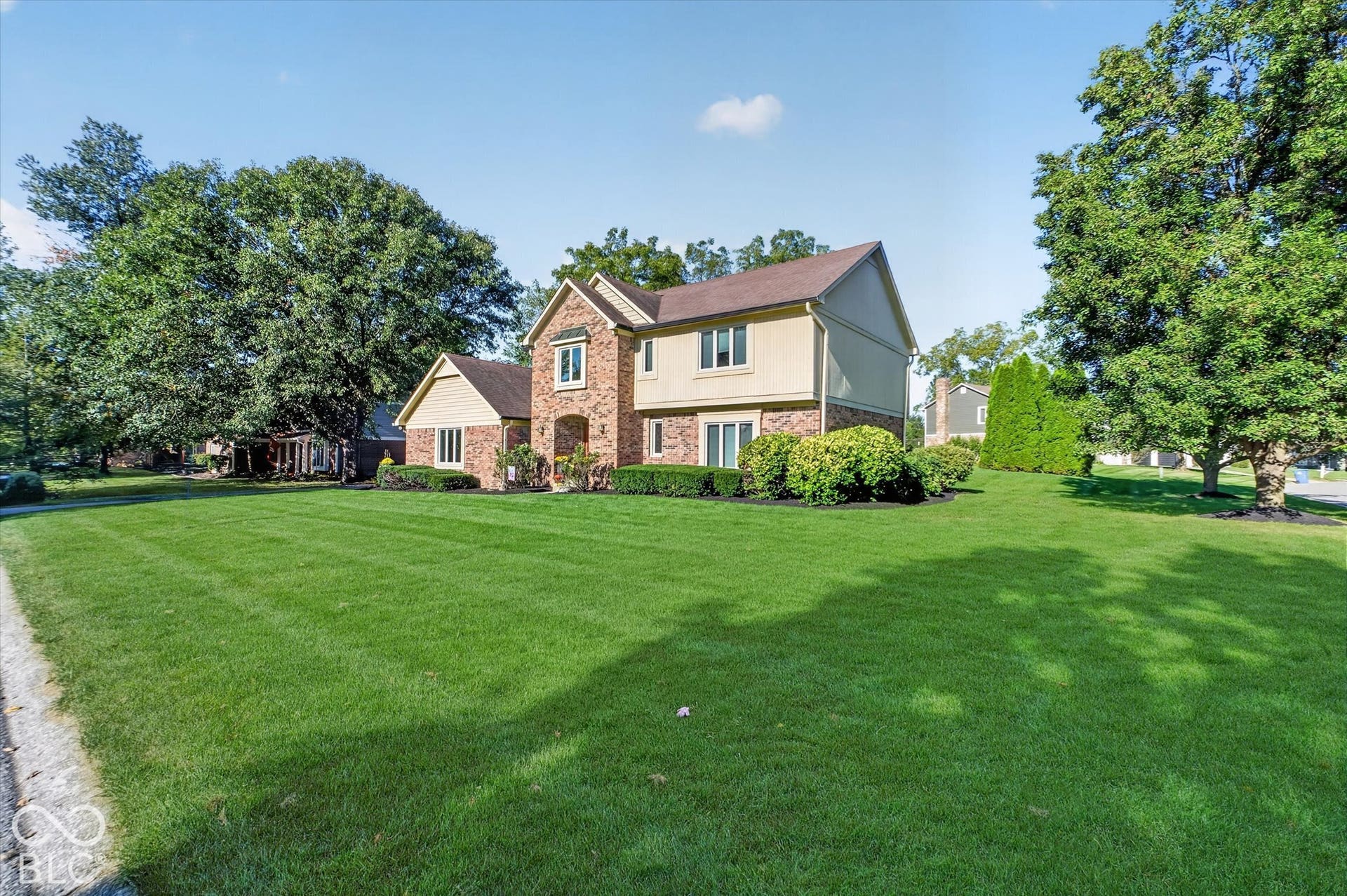 Expansive front lawn with mature trees and established landscaping