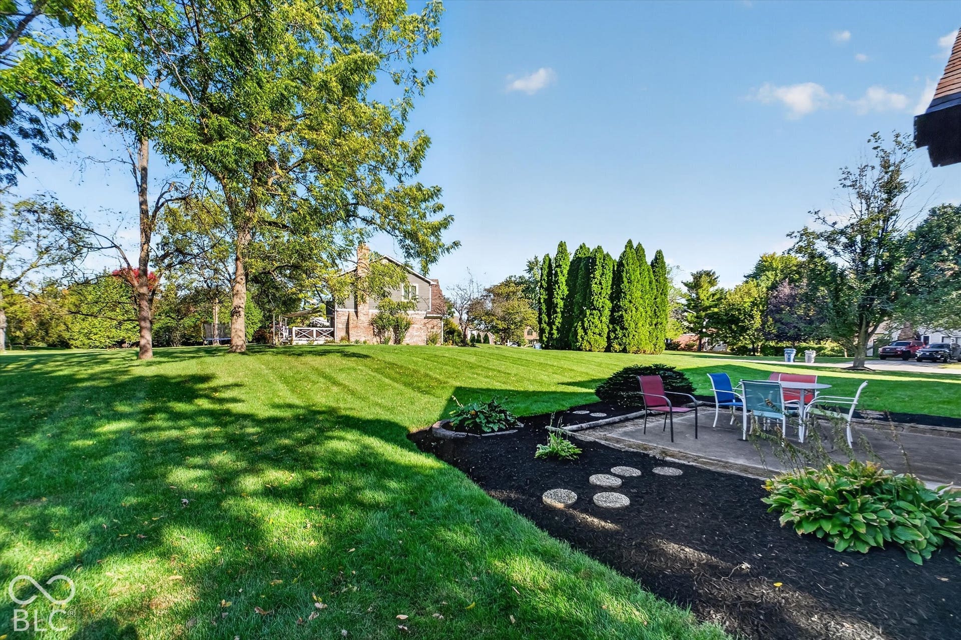 Manicured lawn with mature trees and a paved patio area