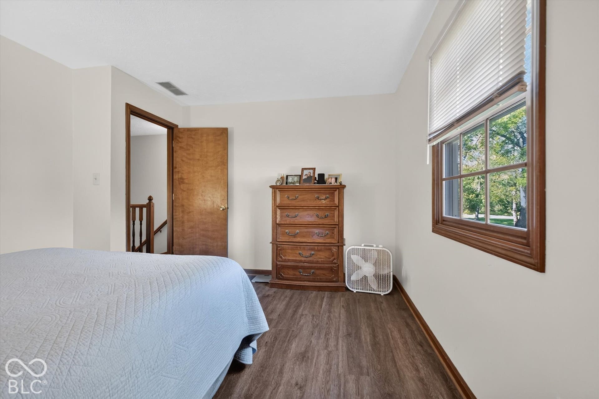 Wood-finish flooring, white walls, and a window with blinds