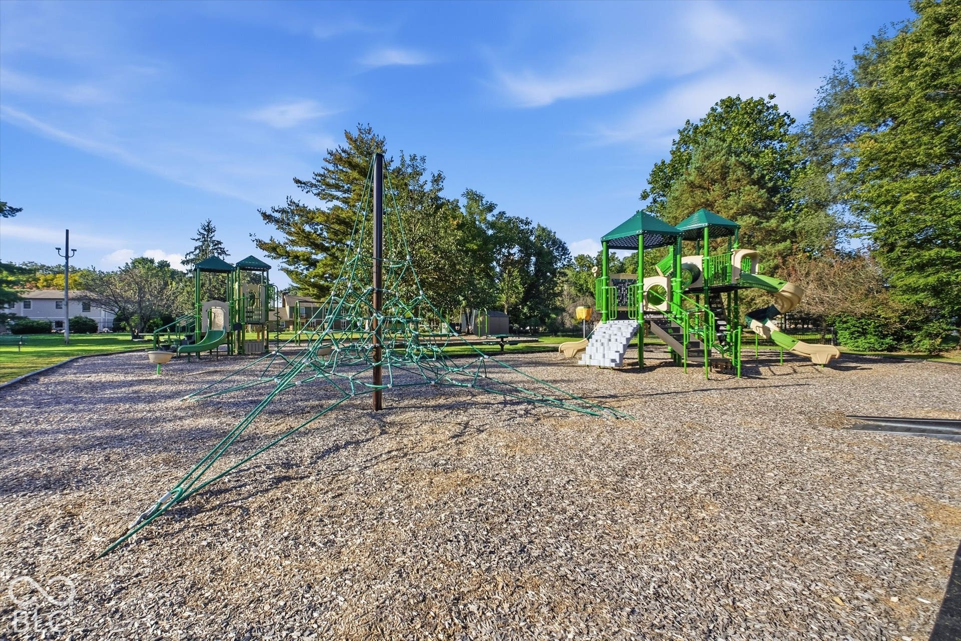 Community playground featuring multiple slides, climbing structures, and a rope climbing pyramid