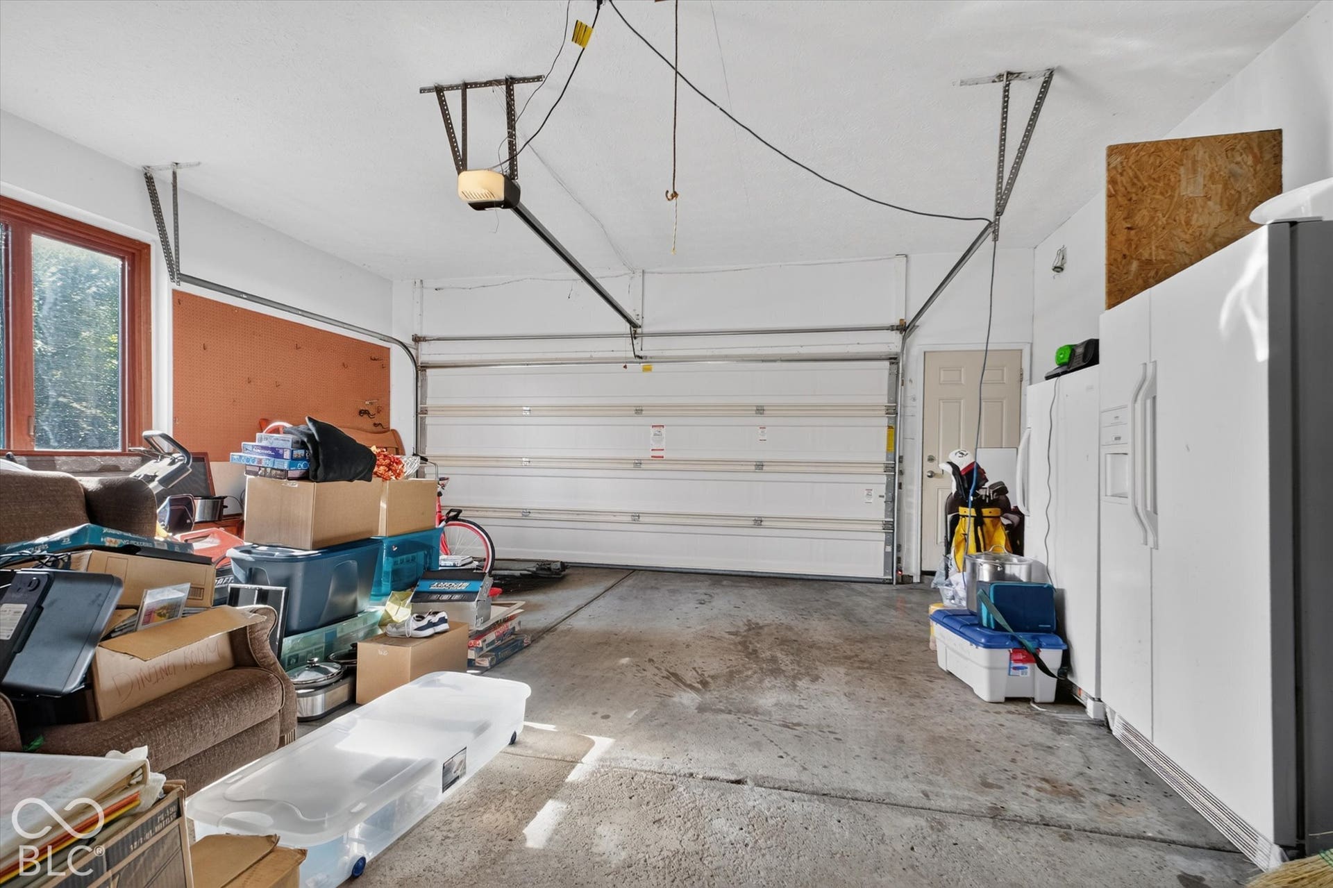 Garage with concrete flooring, automatic overhead door, and a single window