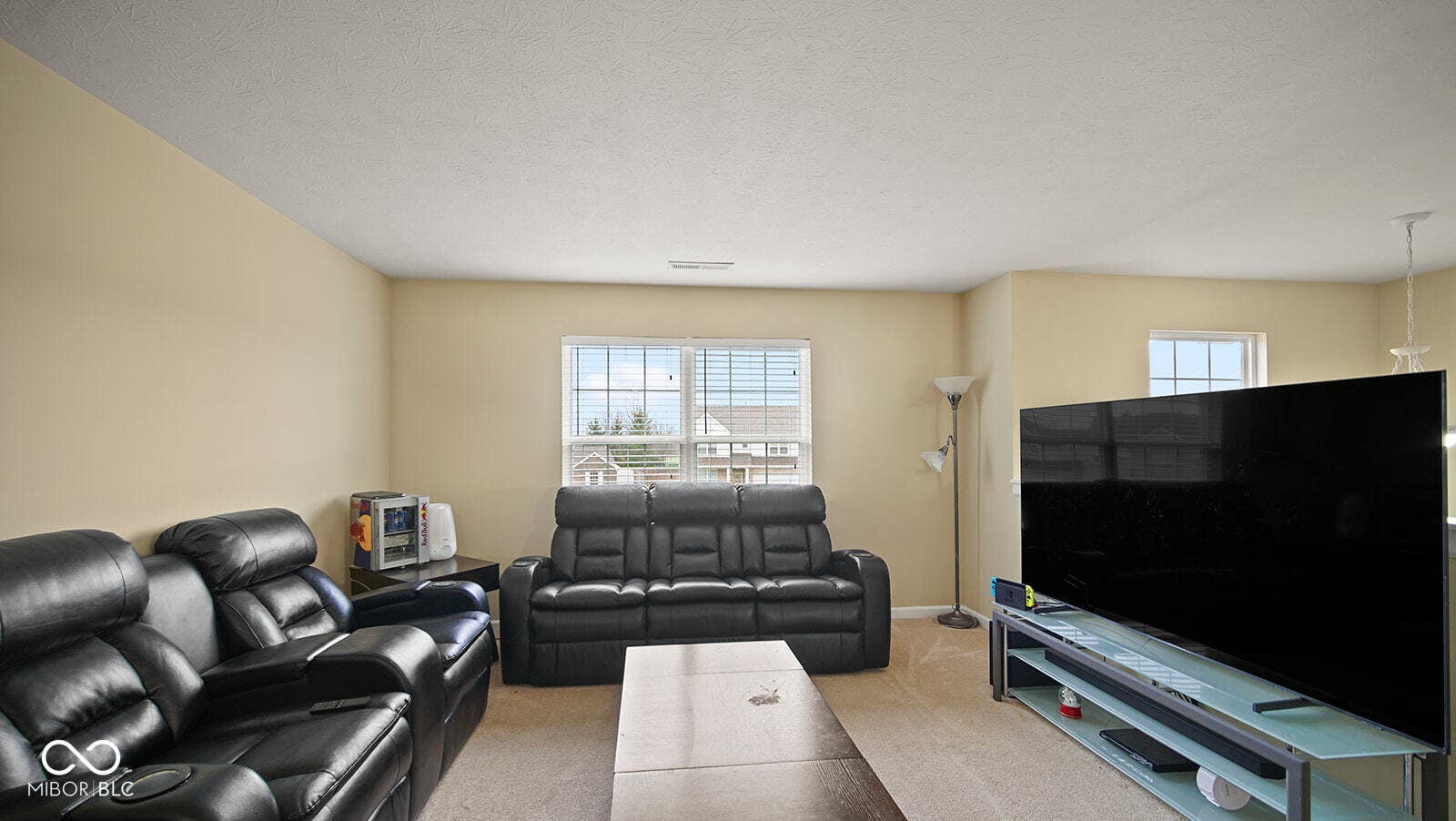 living area featuring light colored carpet, visible vents, baseboards, and a textured ceiling