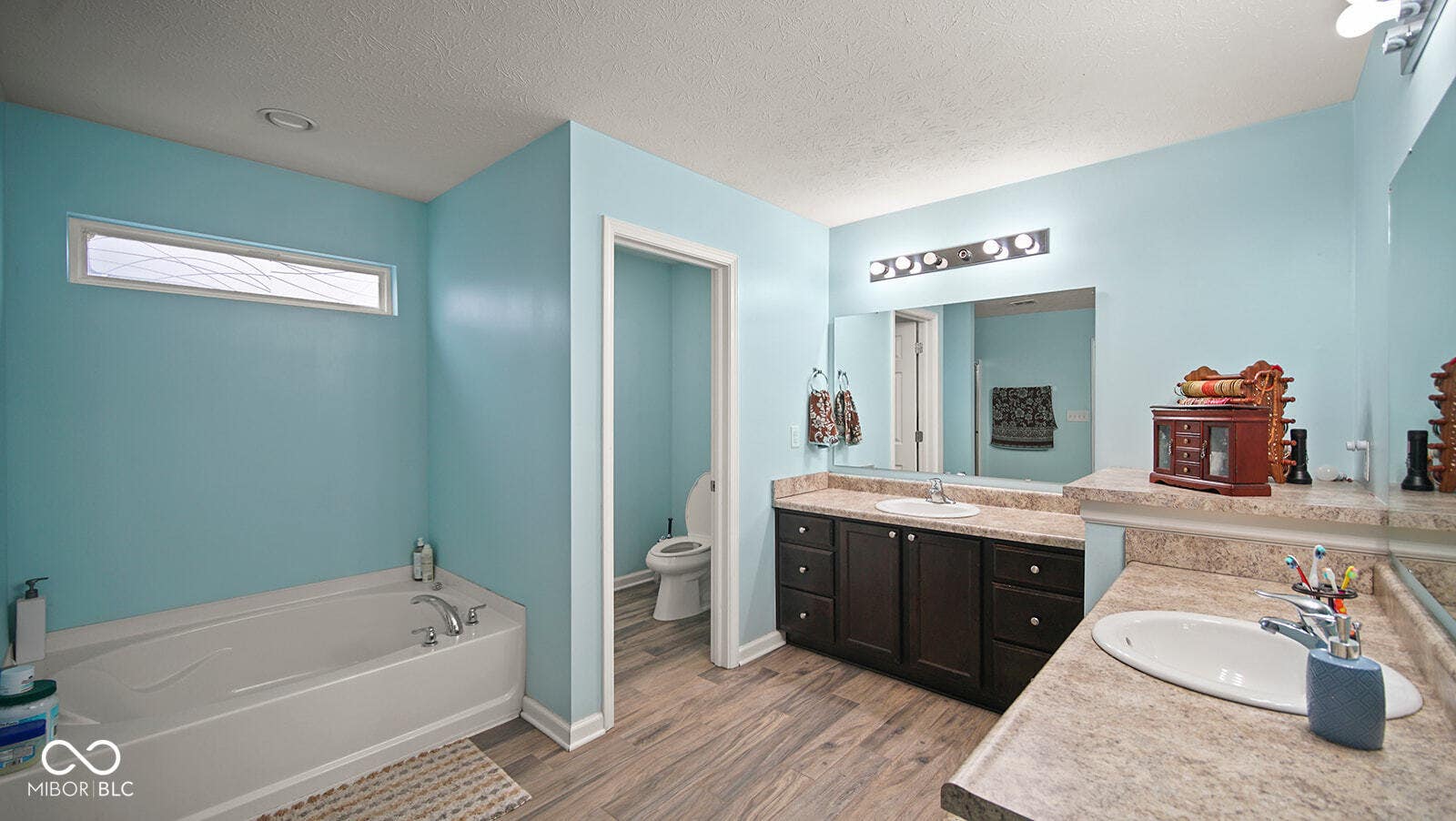 bathroom featuring toilet, vanity, a garden tub, wood finished floors, and a textured ceiling