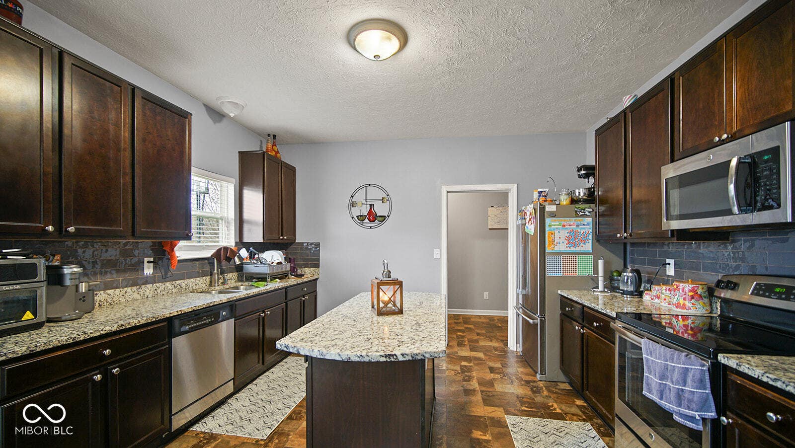 kitchen with light stone countertops, a sink, a center island, and appliances with stainless steel finishes