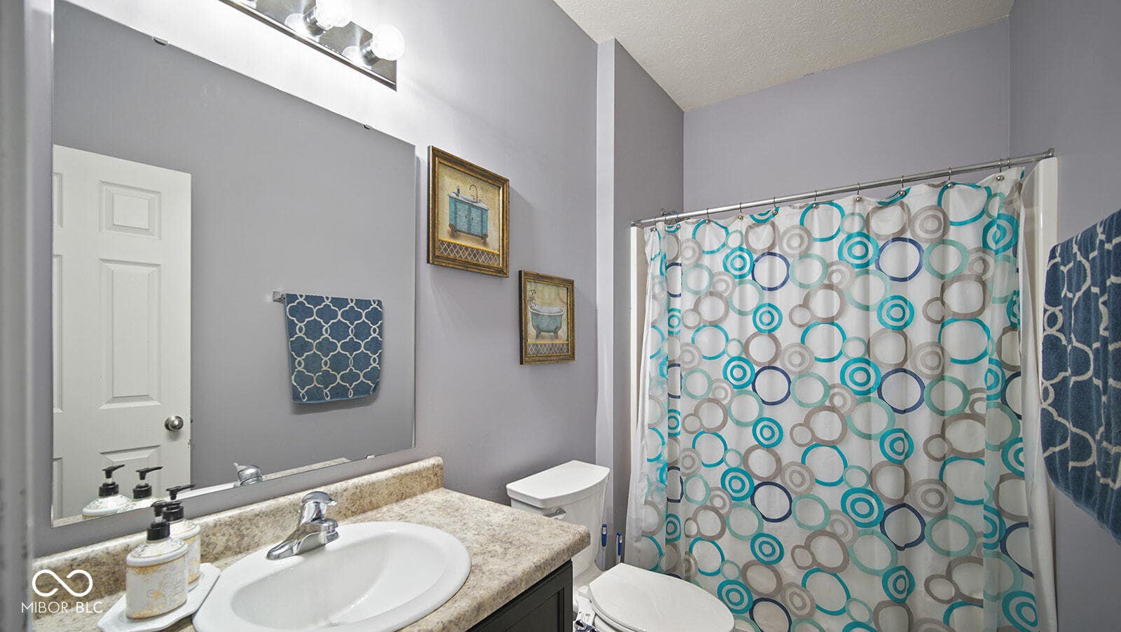 full bath with toilet, vanity, curtained shower, and a textured ceiling