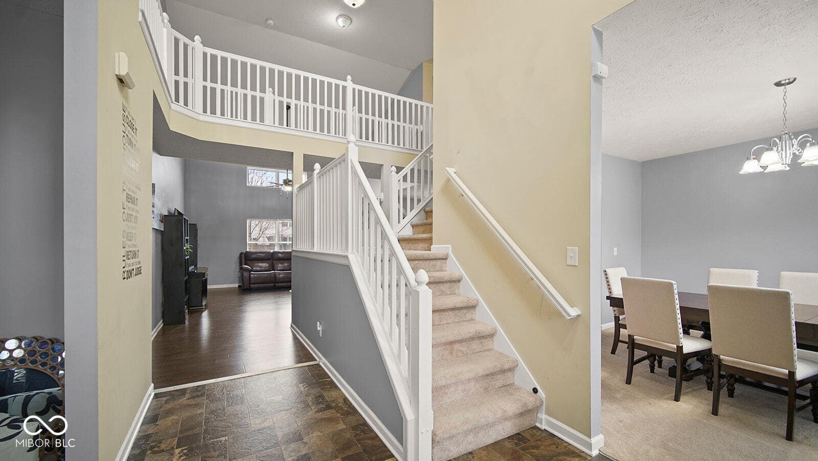 stairway with a notable chandelier, a high ceiling, a textured ceiling, stone finish floor, and baseboards