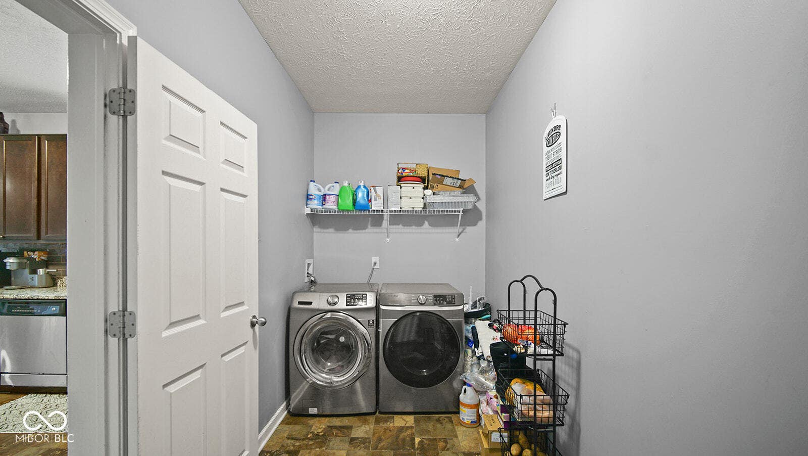 washroom with washing machine and clothes dryer, laundry area, stone finish flooring, and a textured ceiling
