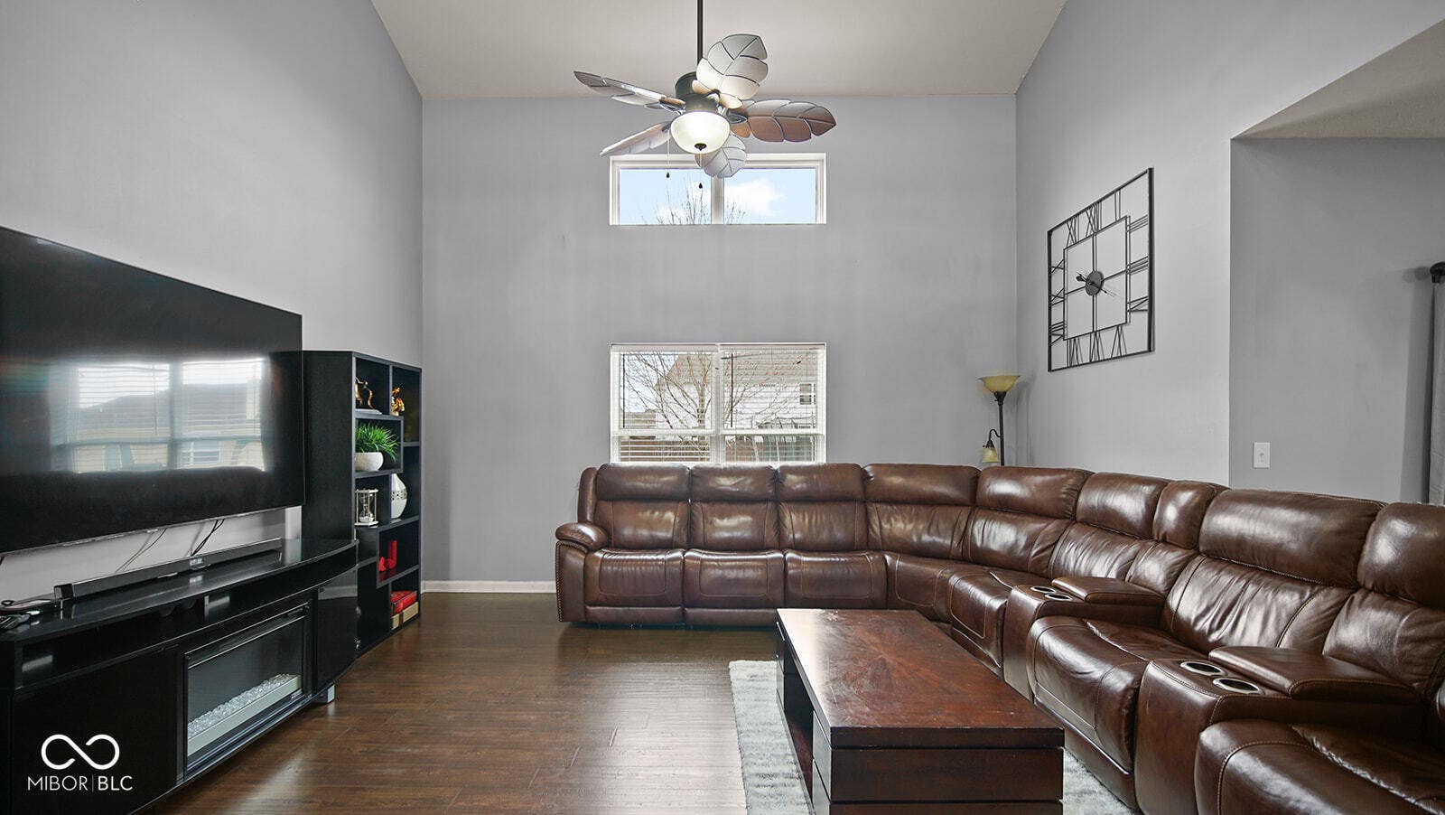 living room with a high ceiling, a ceiling fan, plenty of natural light, and dark wood-style floors