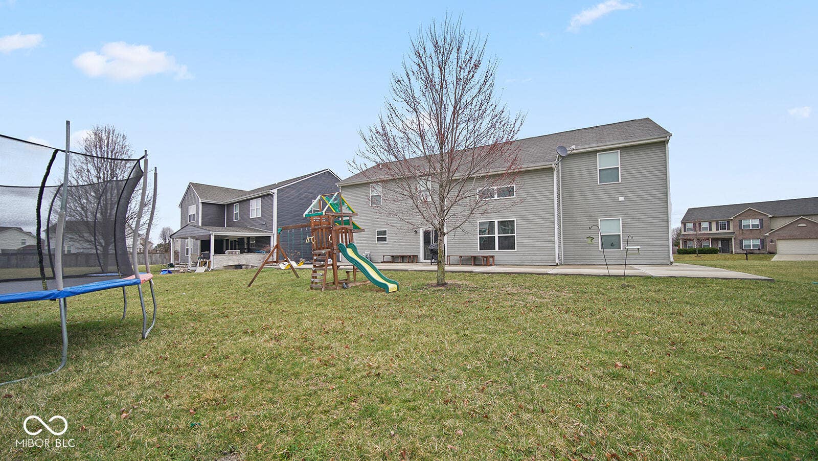 back of property featuring a playground, a patio, a trampoline, a residential view, and a lawn