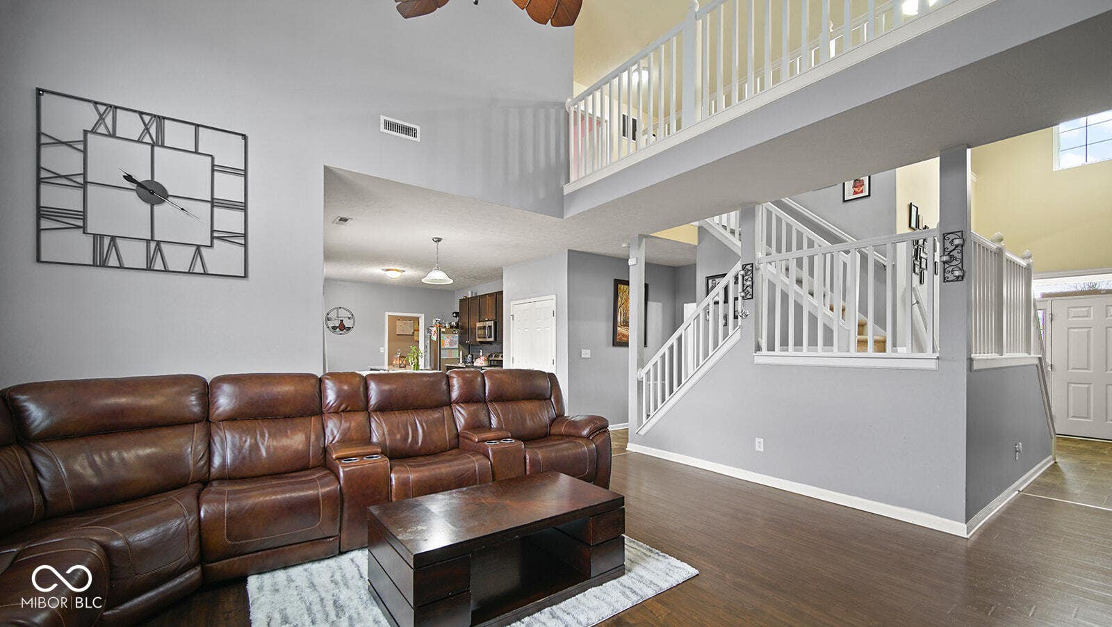 living area featuring wood finished floors, a towering ceiling, baseboards, and visible vents
